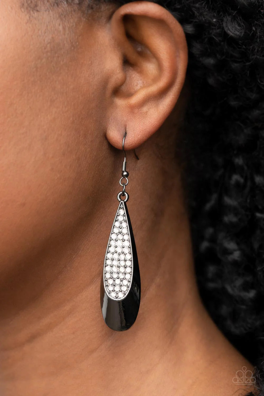Paparazzi Accessories Prismatically Persuasive - Black The front of a dramatically curving gunmetal teardrop is encrusted in glassy white rhinestones, resulting in a glitzy lure. Earring attaches to a standard fishhook fitting. Sold as one pair of earring