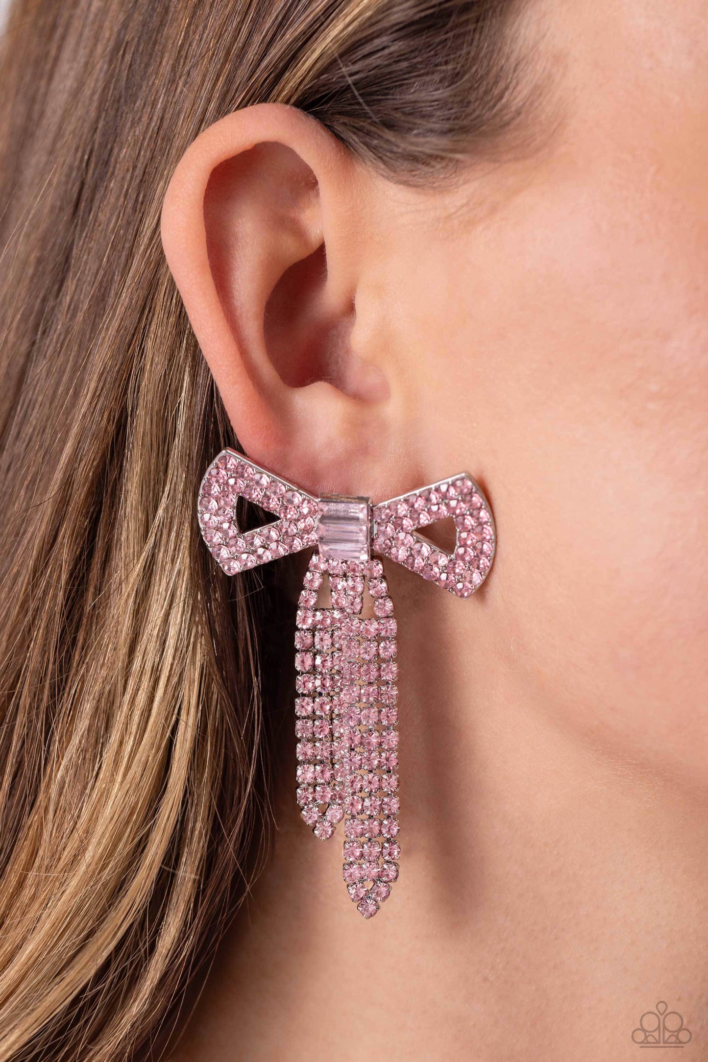 Paparazzi Accessories Just Bow With It - Pink Featuring silver square fittings, high-sheen bands of silver, adorned in sparkling pink rhinestones loop into a stunning bow charm, creating a classy statement at the ear. Featured in the center of the classy