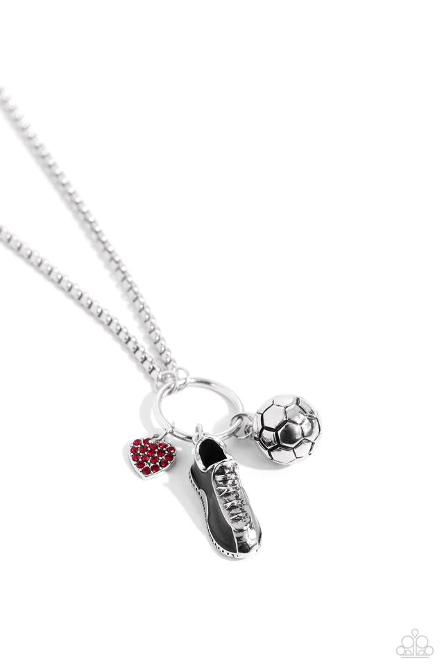 Paparazzi Accessories Corner Kick - Red Dangling from a silver hoop attached to silver popcorn chains, three soccer-inspired charms, including a silver soccer ball, black-painted cleat, and red rhinestone-encrusted heart, swing for a sporty finish. Featur