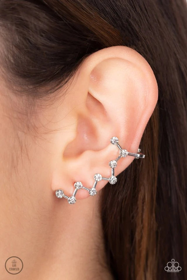 Paparazzi Accessories Clamoring Constellations - White Strategically placed white rhinestones are connected by dainty silver bars as they zigzag up the ear, creating a stellar constellation. Earring attaches to a standard post fitting. Features a dainty c