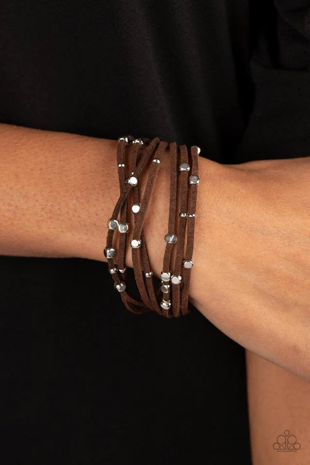 Paparazzi Accessories Clustered Constellations - Brown Row after row of brown suede cords layer around the wrist. Varying sizes of shiny silver studs coalesce across the cords in an out-of-this-world pattern for a starry statement. Features a magnetic clo