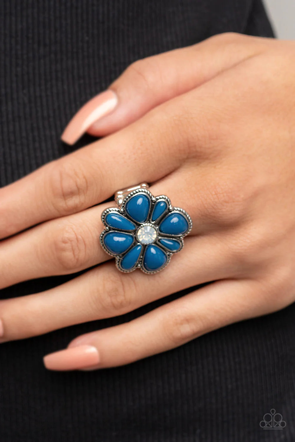 Paparazzi Accessories Meadow Mystique - Blue Featuring asymmetrical cuts, glassy Mykonos Blue beads bloom from an opal white rhinestone center atop a studded silver backdrop for a colorful floral fashion. Features a stretchy band for a flexible fit. Sold