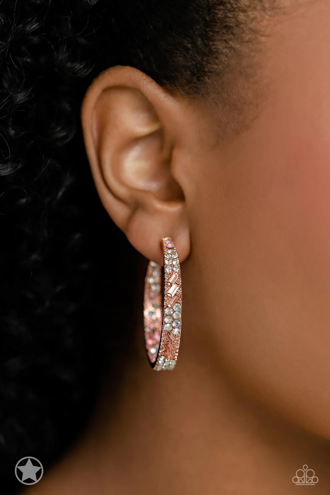 Paparazzi Accessories Glitzy by Association - Copper The front facing surface of a chunky shiny copper hoop is dipped in brilliantly sparkling iridescent, peach, and white rhinestones while light-catching texture wraps around the back. The interior of the