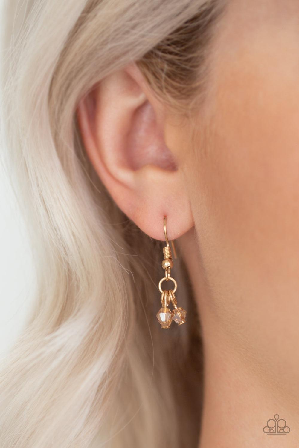 Paparazzi Accessories First Class Fringe - Gold Varying in length, mismatched gold chains stream from the bottom of a classic gold chain. Faceted golden crystal-like beads sporadically dot the free-falling chains, creating a statement-making fringe below