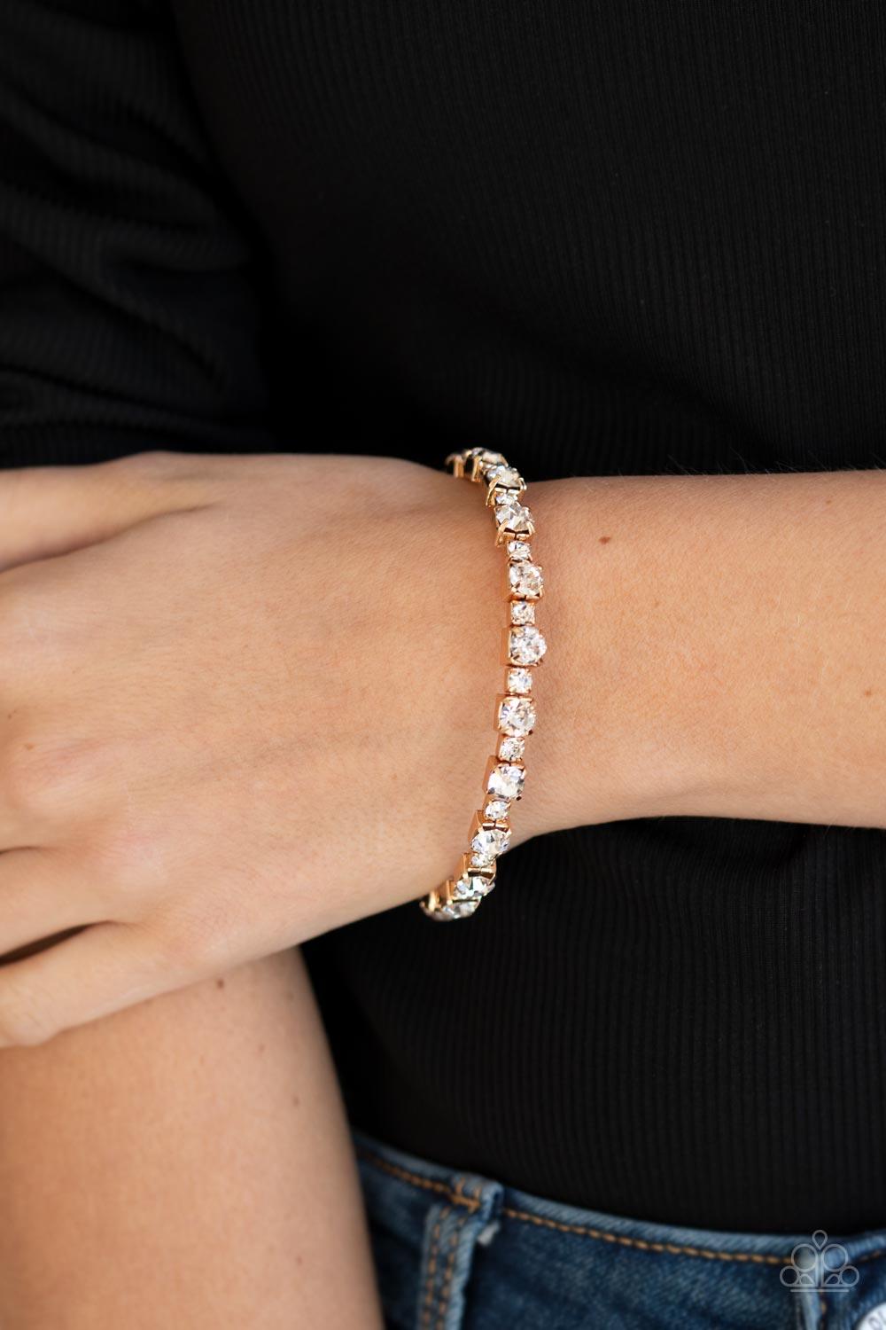 Paparazzi Accessories Photo Op - Gold Featuring gold square fittings, dainty and classic white rhinestones delicately alternate along a flexible wire, coiling into a glamorous centerpiece around the wrist. Sold as one individual bracelet. Jewelry