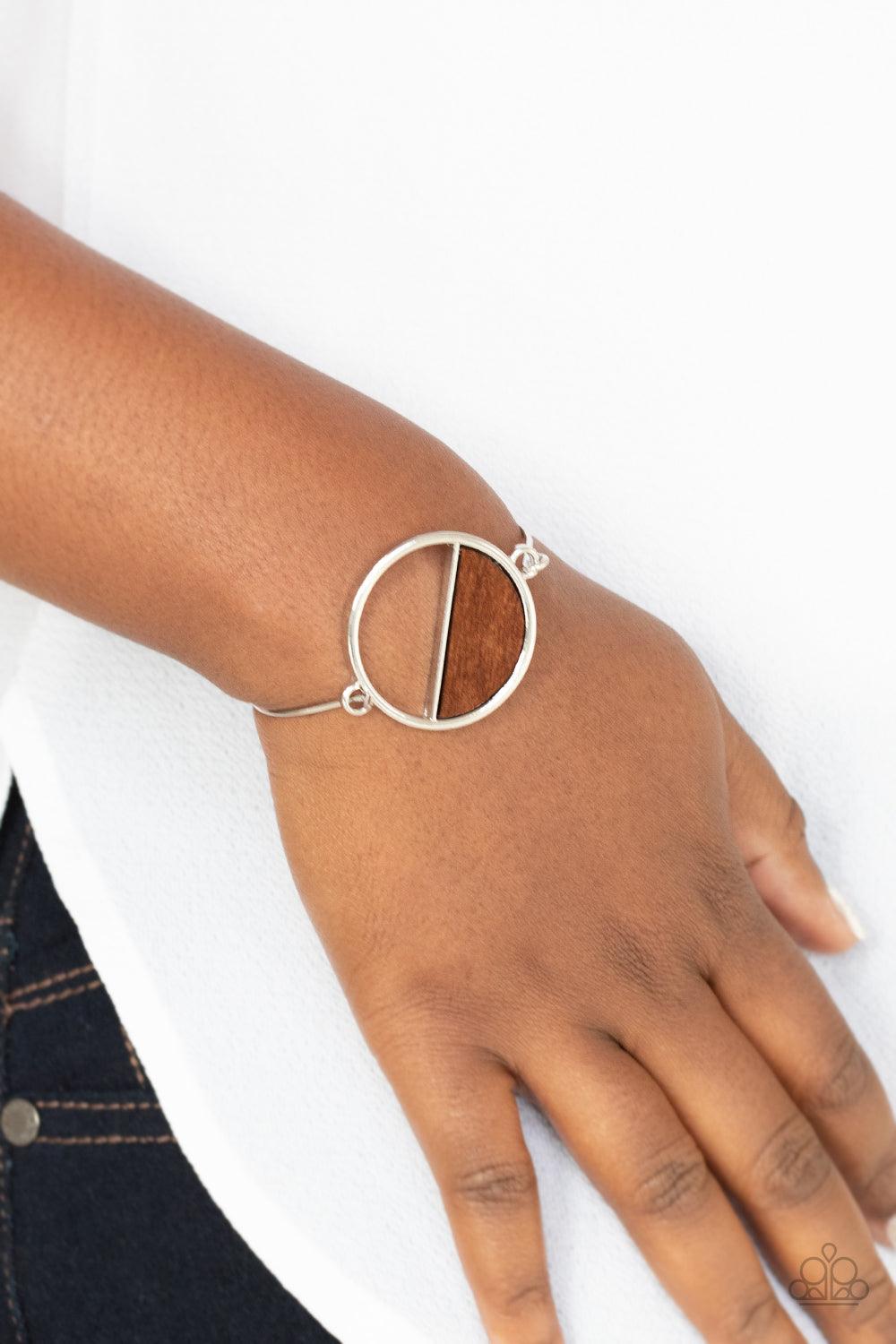Paparazzi Accessories Timber Trade - Brown Attached to a dainty silver bar that curls around the wrist, a crescent shaped wooden accent adorns half of an airy circular centerpiece for a modern twist. Features a toggle closure. Sold as one individual brace