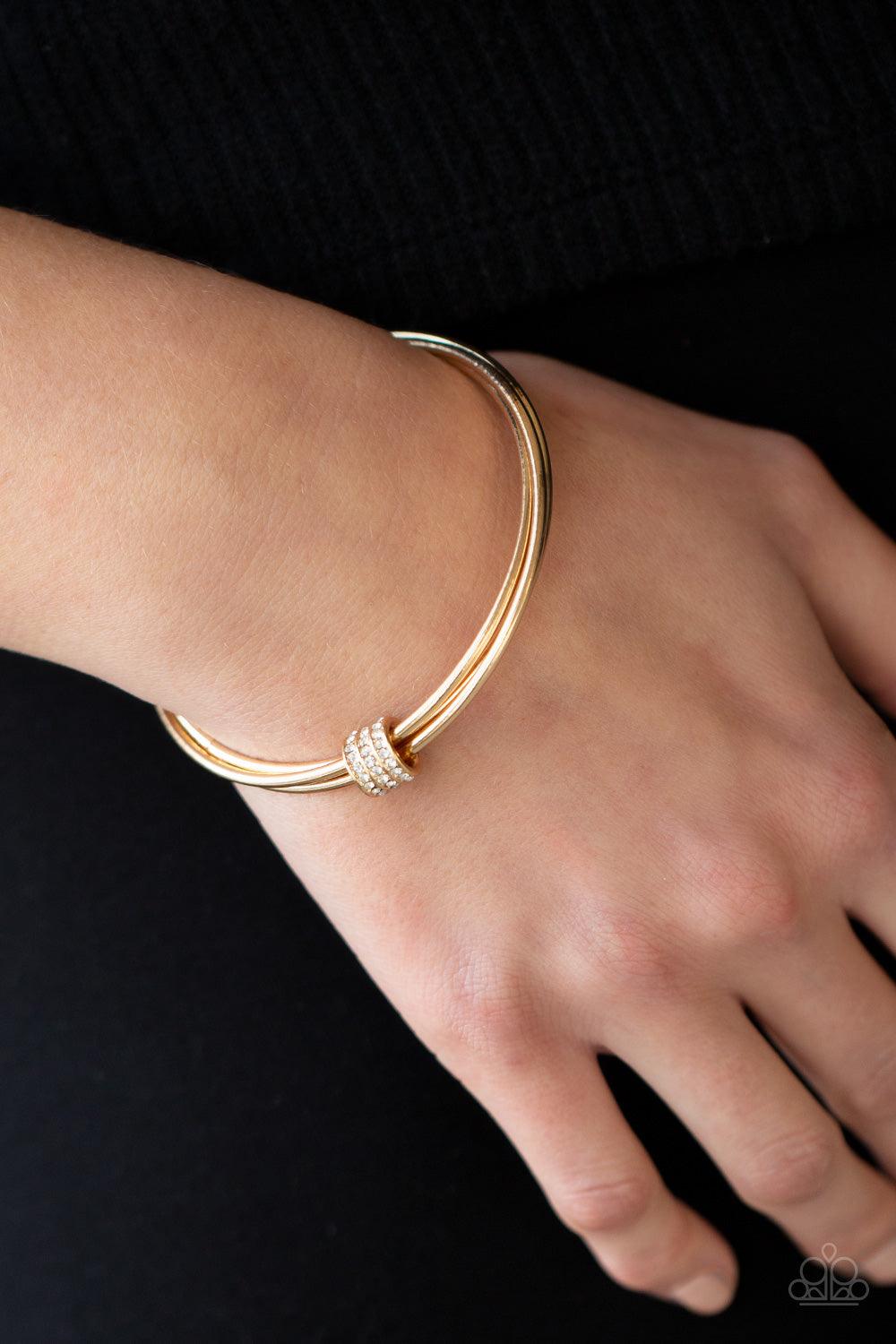 Paparazzi Accessories Roll Out The Rhinestones - Gold A white rhinestone encrusted fitting glides along a trio of gold bangles, creating a solitaire bracelet around the wrist. Sold as one individual bracelet. Jewelry