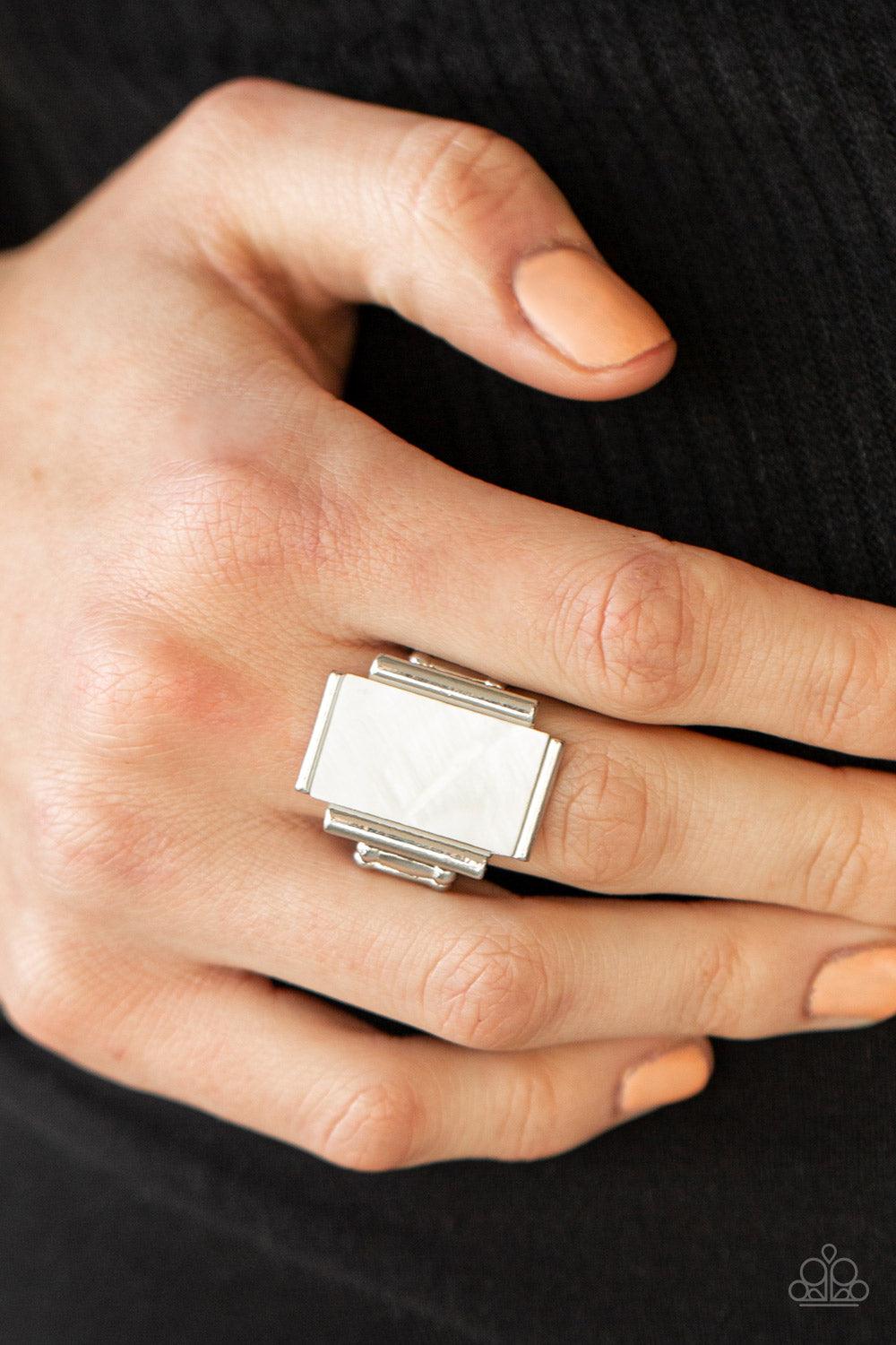 Paparazzi Accessories Mystical Marinas - White Featuring an iridescent shimmer, a white shell-like rectangle is nestled between silver bar-like fittings atop the finger for a mystical look. Features a stretchy band for a flexible fit. Sold as one individu