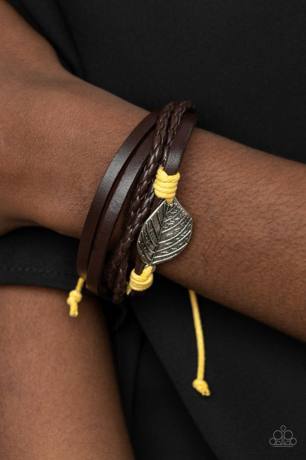 Paparazzi Accessories FROND and Center - Yellow A lifelike silver leaf frame is knotted in place with yellow cording across the front of a dainty brown leather band. Matching plain and braided leather bands join the centerpiece, creating earthy layers aro