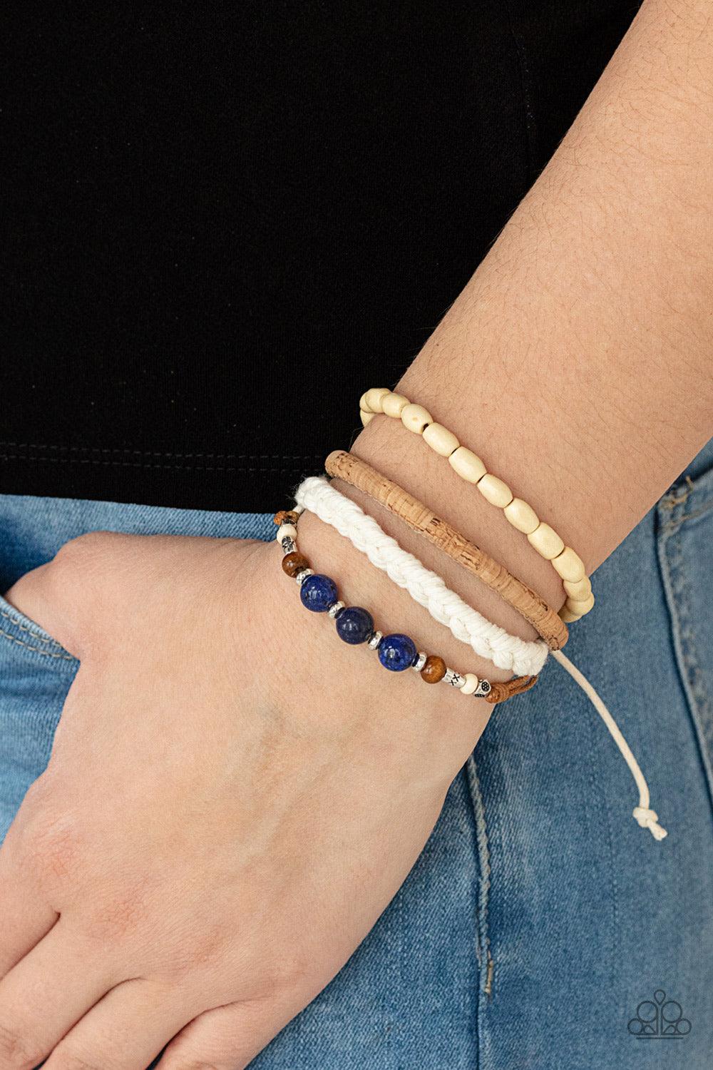 Paparazzi Accessories Natural-Born Navigator - Blue Featuring cork, thread, and wood, mismatched metallic accents, glassy blue stones, and wood beads adorn earthy layers around the wrist for a whimsical look. Features an adjustable sliding knot closure. S