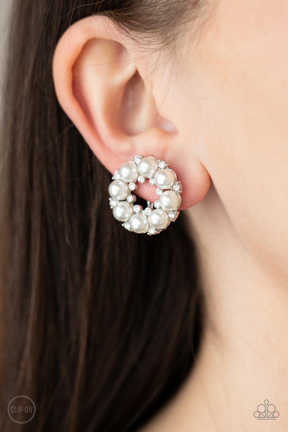 Paparazzi Accessories Roundabout Ritz - White *Clip-On A timeless collection of dainty white rhinestones and classic white rhinestones spin into a bubbly hoop. Earring attaches to a standard clip-on fitting. Sold as one pair of clip-on earrings. Jewelry