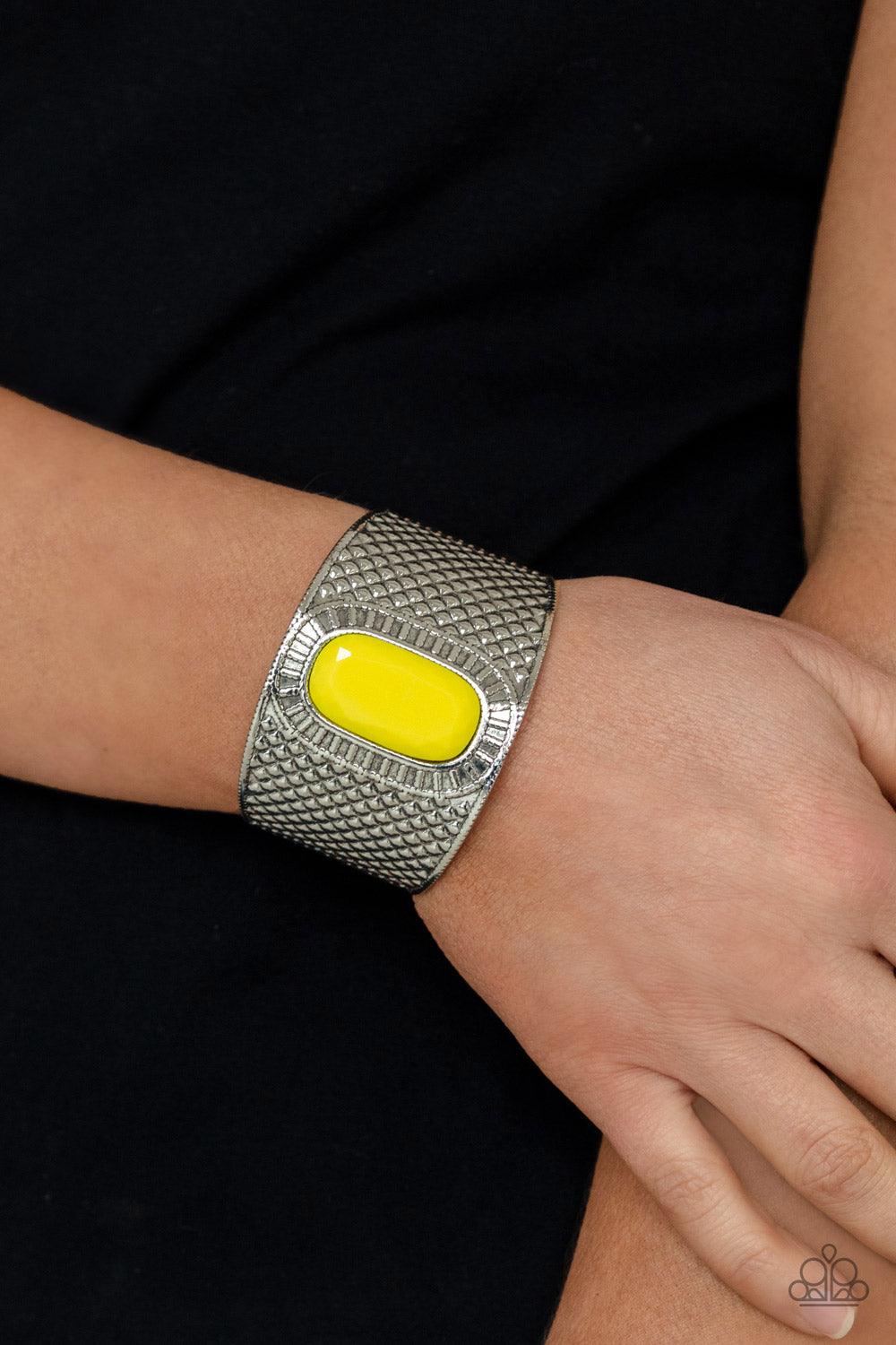 Paparazzi Accessories Poshly Pharaoh - Yellow An oversized faceted Illuminating bead is pressed into the center of a thick silver cuff that is embossed in diamond-like textures, creating a bold tribal inspired centerpiece around the wrist. Sold as one ind