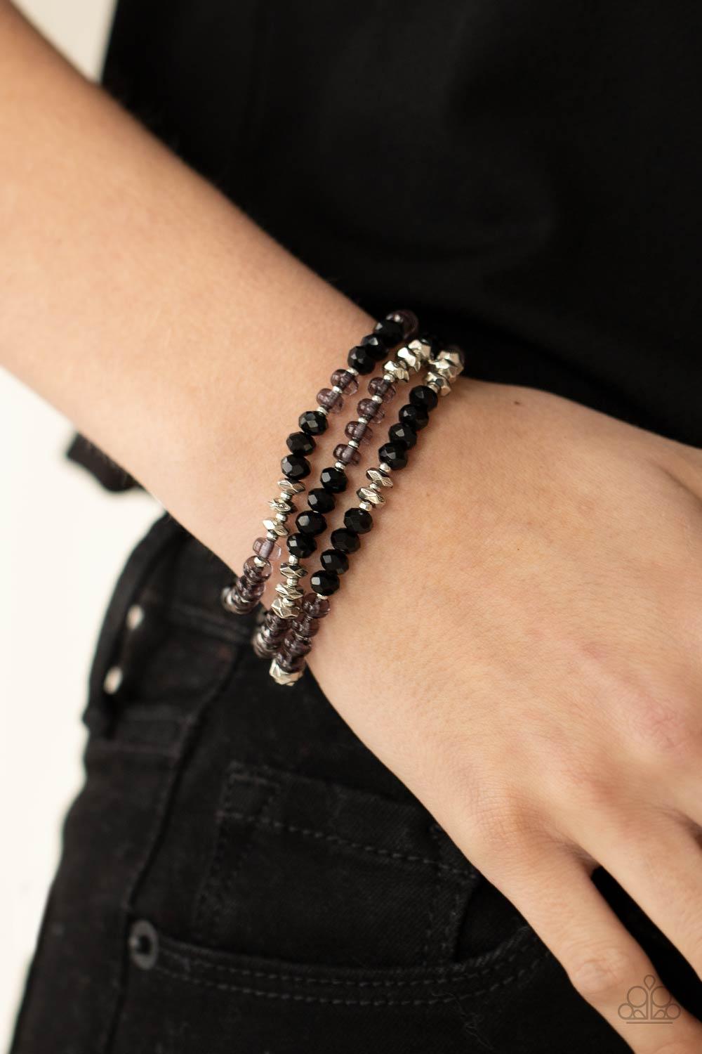 Paparazzi Accessories Stellar Strut - Black Infused with faceted silver beads, a glamorous collection of sparkly black crystals and smoky beads are threaded along stretchy bands around the wrist, creating glittery layers. Sold as one set of three bracelet