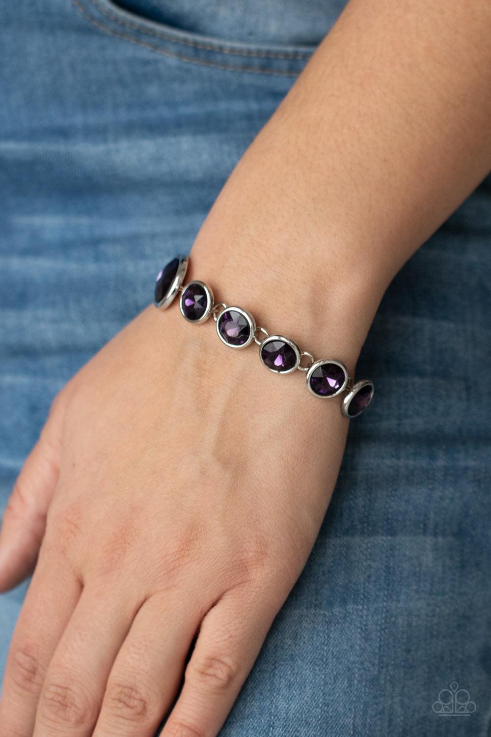 Paparazzi Accessories Lustrous Luminosity - Purple Featuring sleek silver fittings, an oversized collection of sparkly purple gems delicately link around the wrist. The centermost gem is slightly larger than the rest, adding a glamorous finish. Features a
