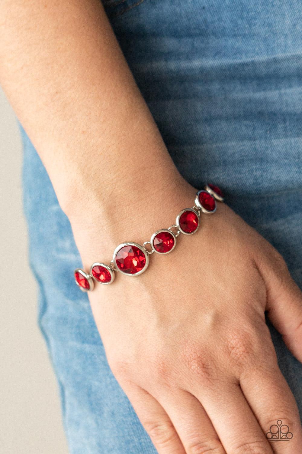 Paparazzi Accessories Lustrous Luminosity - Red Featuring sleek silver fittings, an oversized collection of fiery red gems delicately link around the wrist. The centermost gem is slightly larger than the rest, adding a glamorous finish. Features an adjust