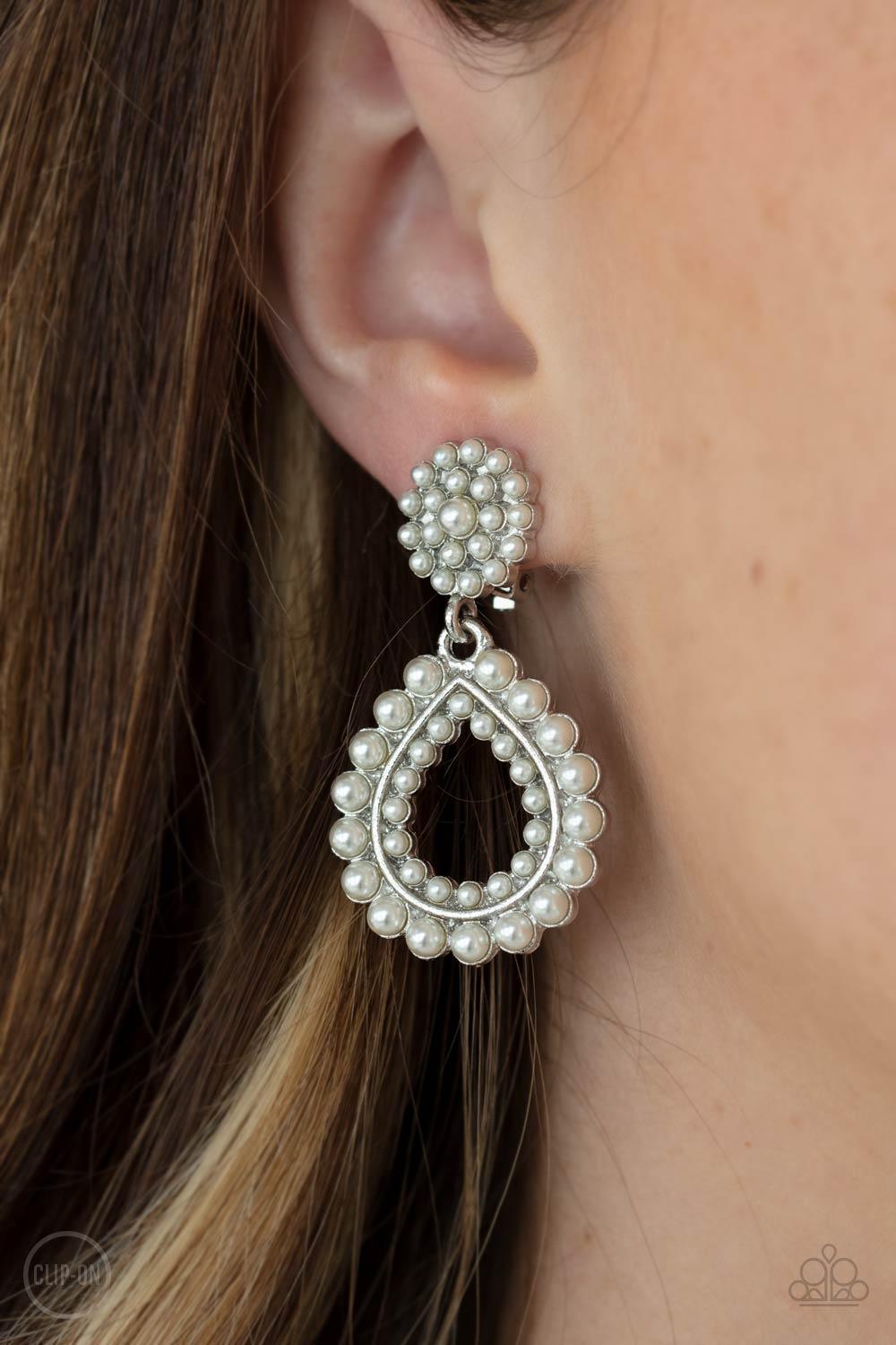 Paparazzi Accessories Discerning Droplets - White *Clip-On Droplets of pearls dot the surface of a silver teardrop frame that suspends from a round pearl encrusted disc for a classic finish. Earring attaches to a standard clip-on fitting. Sold as one pair