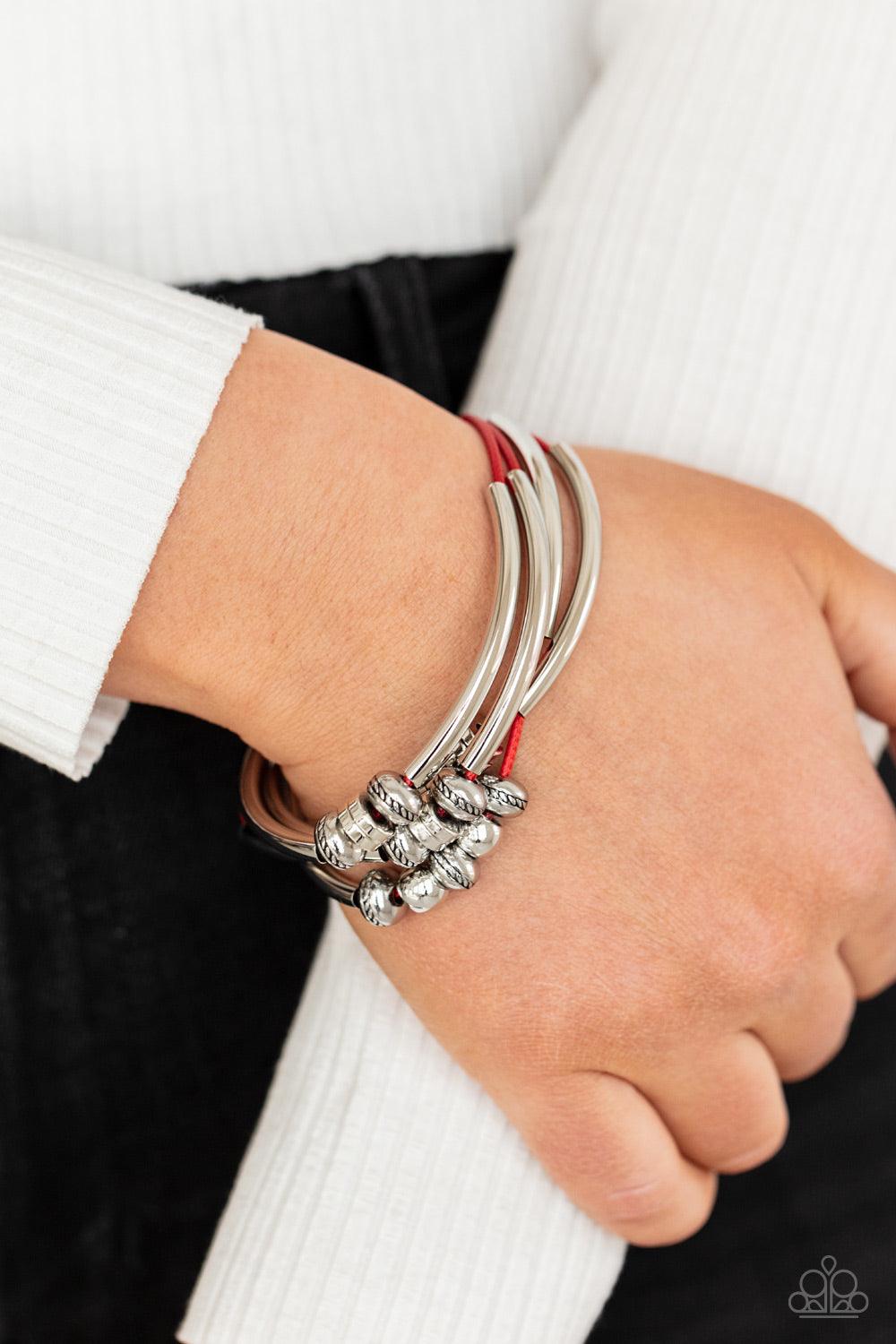 Paparazzi Accessories We Aim To Please - Red Multiple strands of red cord are fitted with long, curved cylinders that meet in the middle. The sliding bars are separated by small antiqued silver loops that mimic pipe fittings, making this a perfect additio