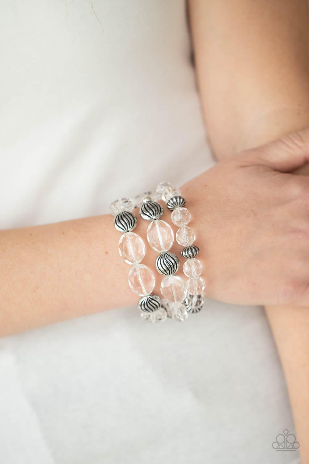 Paparazzi Accessories Crystal Charisma - White A mismatched collection of sparkly white crystal-like beads and textured silver accents are threaded along stretchy bands around the wrist, creating glamorous layers. Sold as one set of three bracelets. Jewel