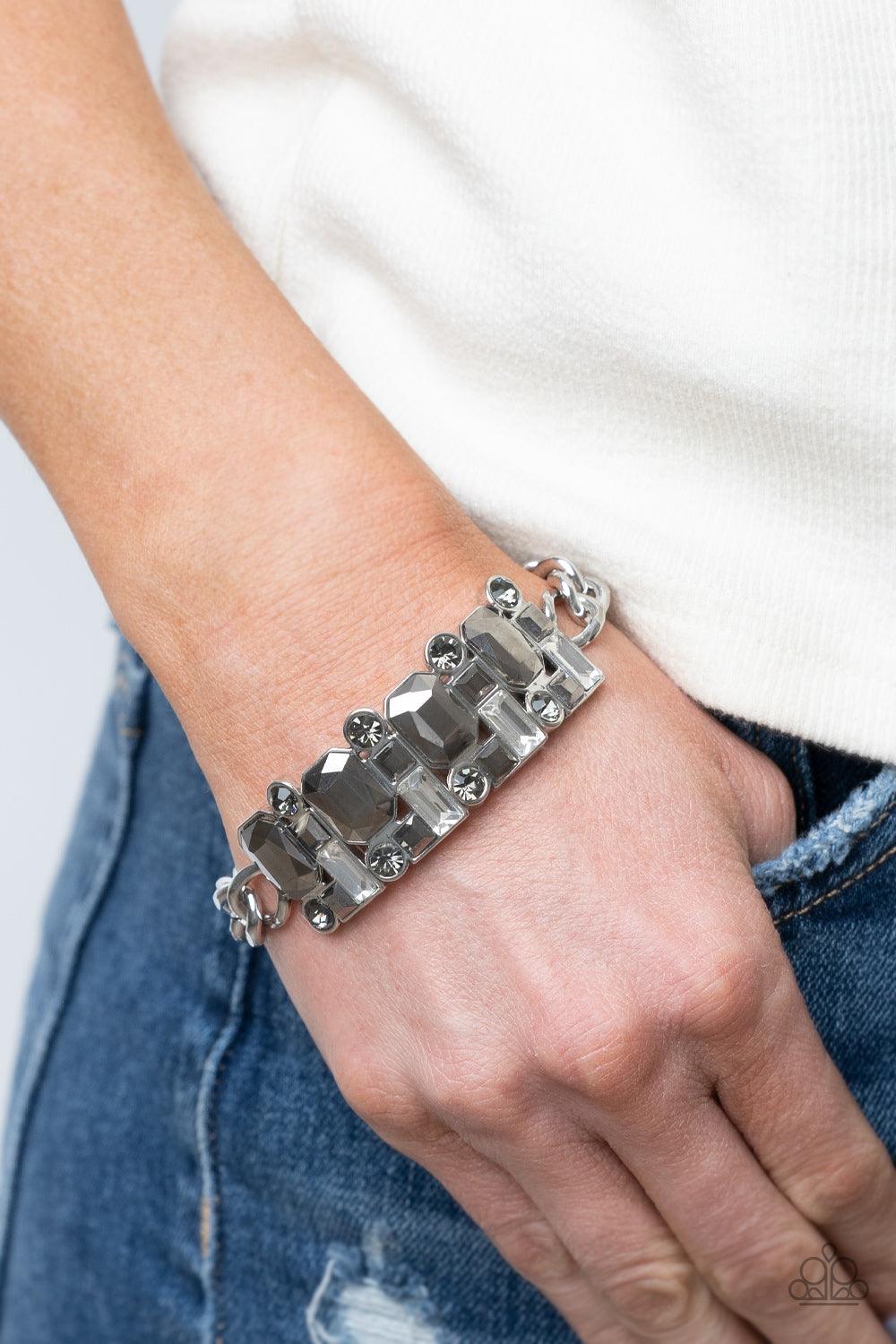 Paparazzi Accessories Urban Crest - Silver A mismatched collision of hematite, smoky, and white rhinestone encrusted frames are threaded along a stretchy band that attaches to a chunky strand of silver chain, creating jaw-dropping dazzle across the front