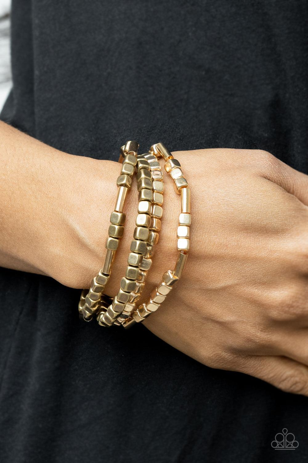 Paparazzi Accessories Metro Materials - Multi Lightweight and flirty, two strands of gold and brass square beads interspersed with gold cylinders, are paired with two strands of gold and brass cubes. The four stretchy bracelets come together to create an