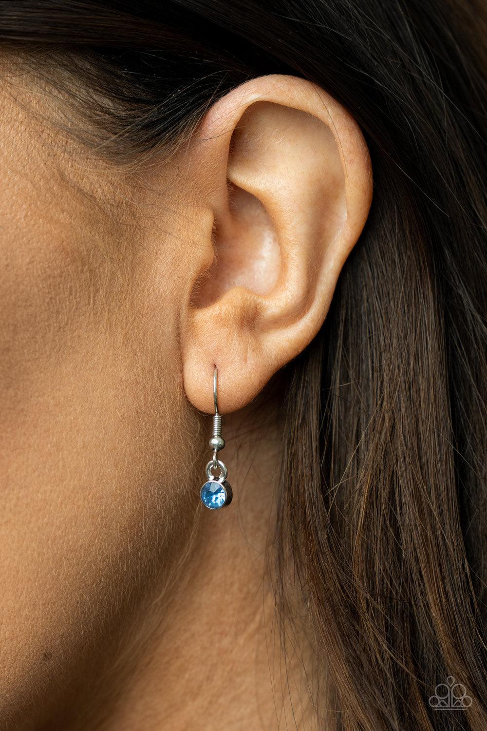 Paparazzi Accessories A Mothers Heart - Blue The word "Mom" floats inside an airy heart-shaped frame. A second heart encrusted with dewy blue rhinestones encircles the centerpiece as it sways from a lengthened silver chain for a sweet token of love. Featu