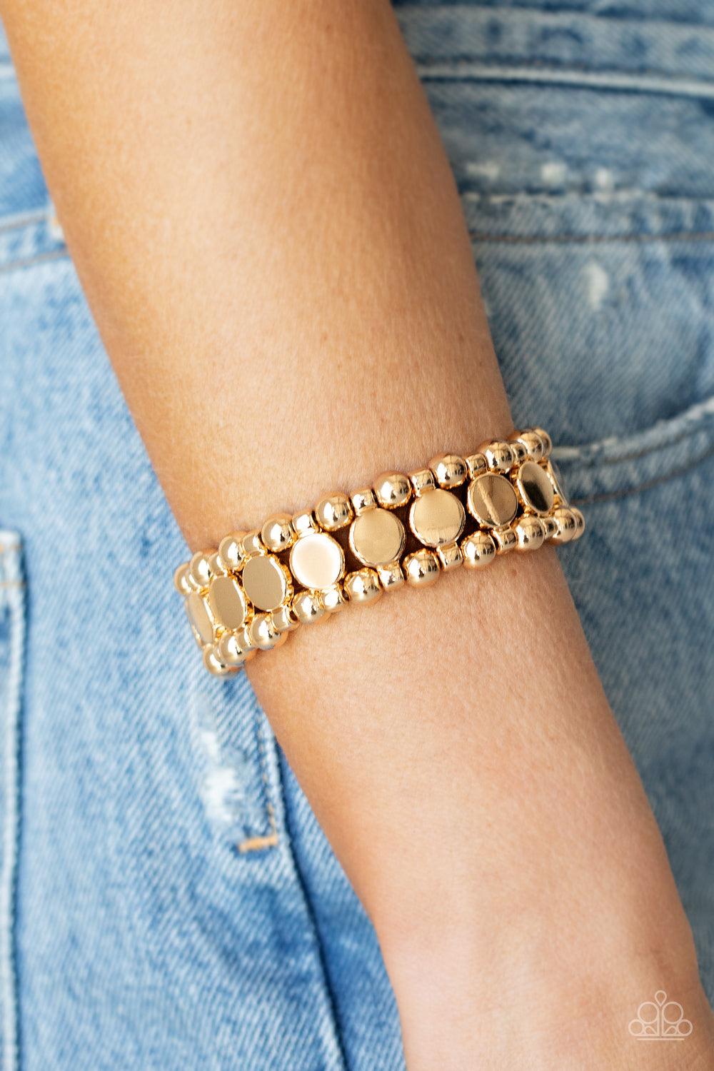 Paparazzi Accessories Metro Magnetism - Gold Glistening gold disc fittings and pairs of classic gold beads are threaded along stretchy bands around the wrist that connect into a bold industrial display around the wrist. Sold as one individual bracelet. Je