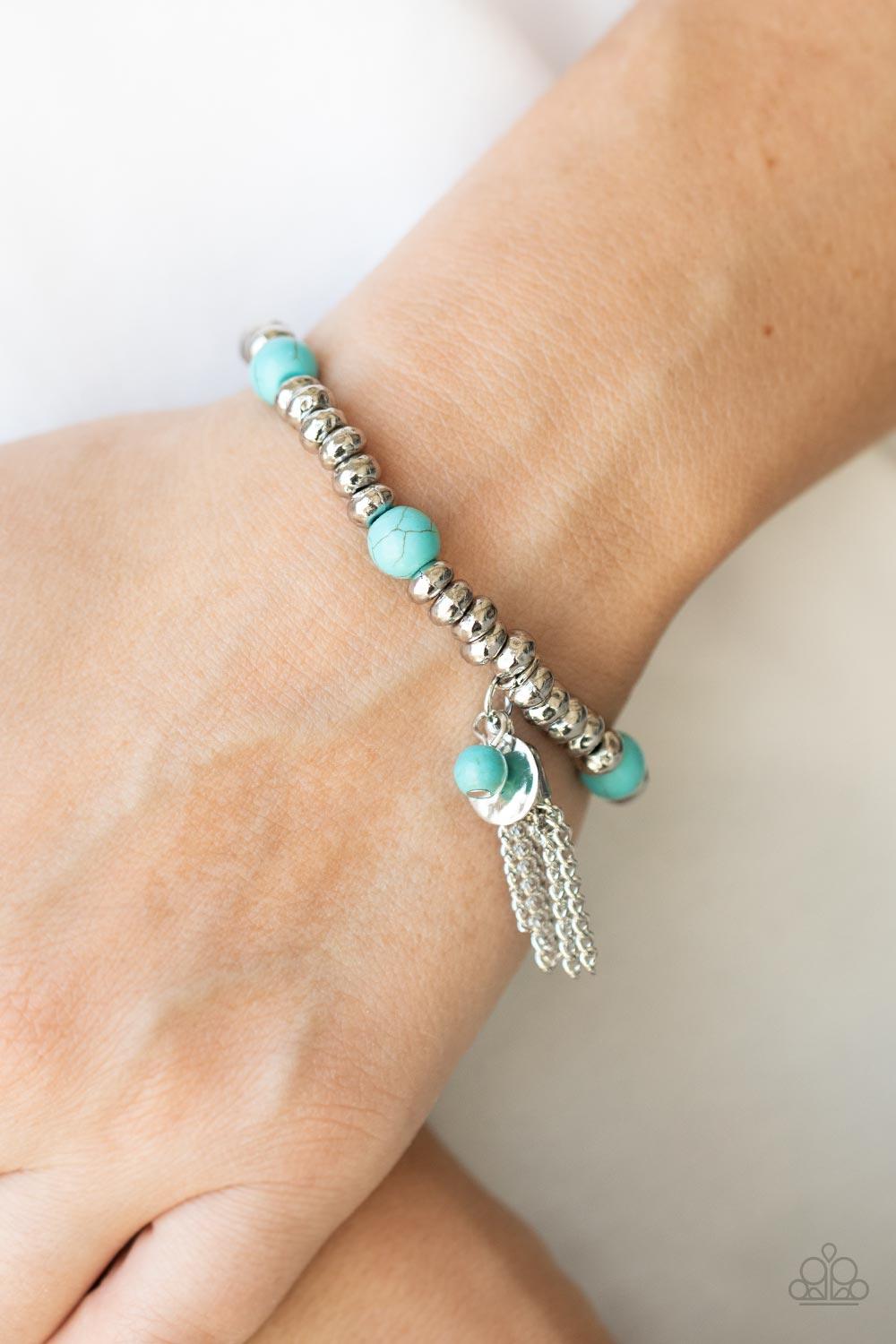 Paparazzi Accessories Whimsically Wanderlust - Blue An earthy collection of hammered silver beads and round turquoise stones are threaded along a stretchy band around the wrist. A dainty silver tassel, hammered silver disc, and a turquoise stone swing fro