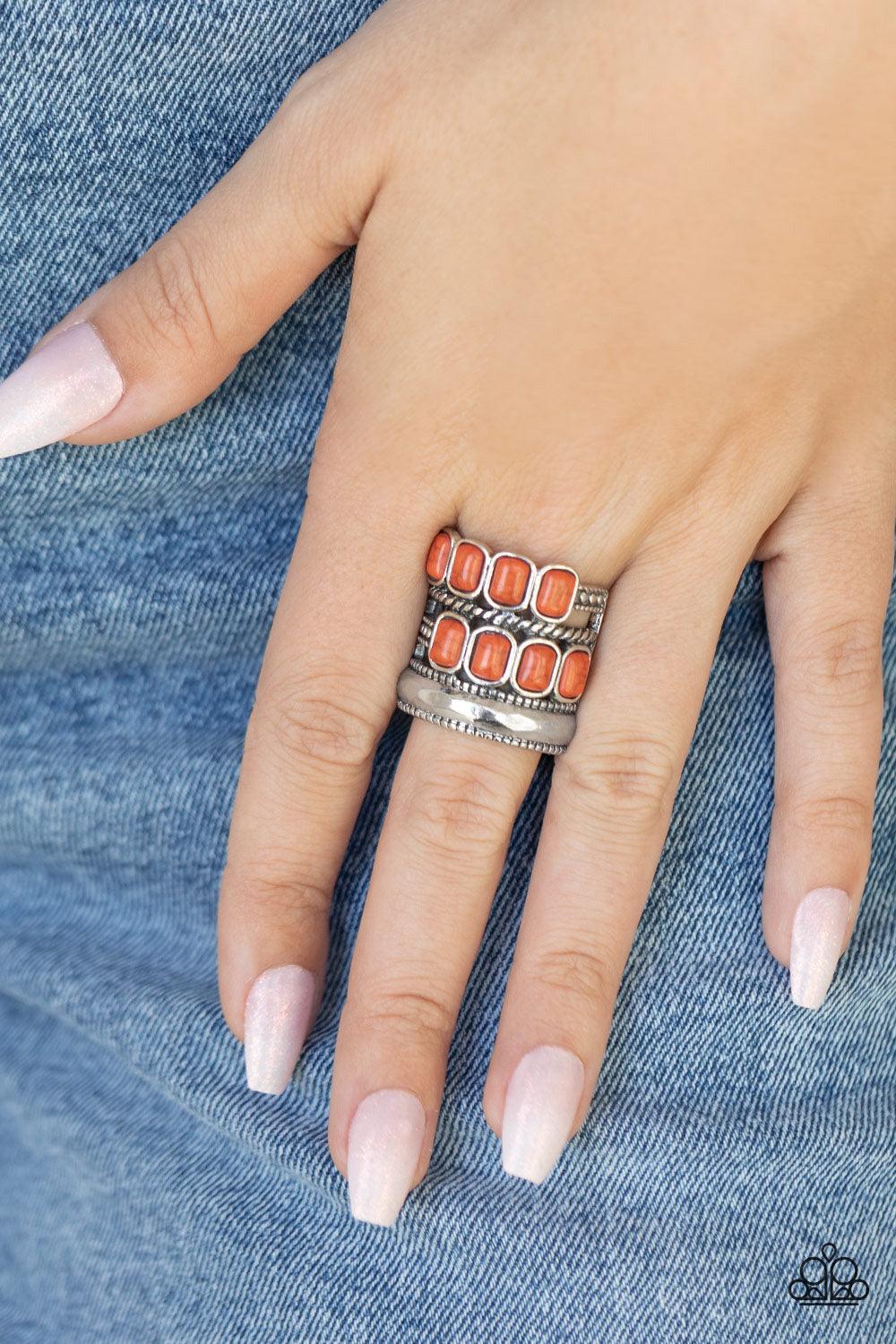 Paparazzi Accessories Mojave Monument - Orange Mismatched rows of Adobe rectangular stone beads, twisted silver and studded silver bars, and a faceted silver band haphazardly layer across the finger, coalescing into a colorfully rustic centerpiece. Featur