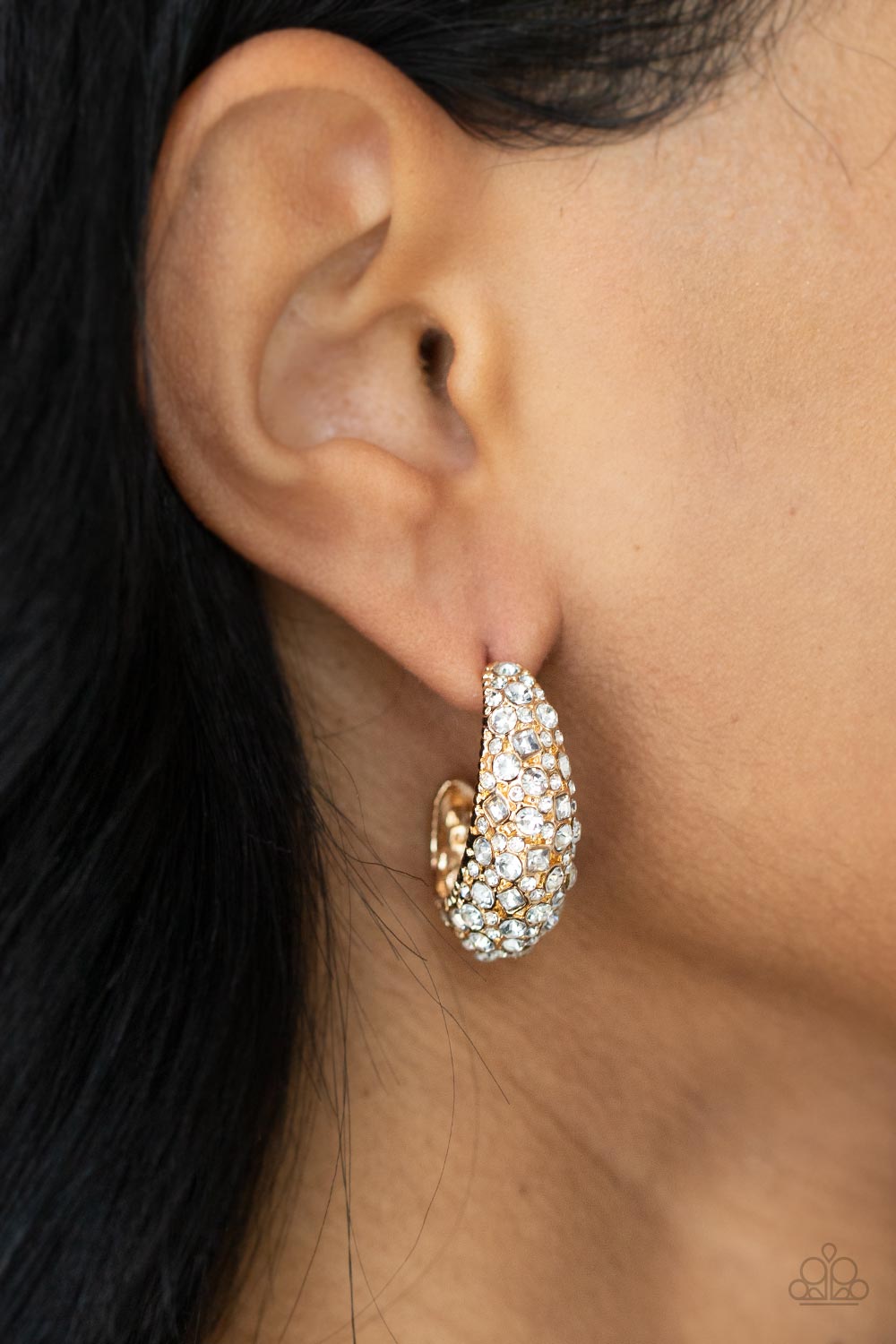 Paparazzi Accessories Glamorously Glimmering - Gold Featuring a beveled surface, a thick hammered gold hoop is haphazardly encrusted in round and square white rhinestones for a glamorously glittery finish. Earring attaches to a standard post fitting. Hoop