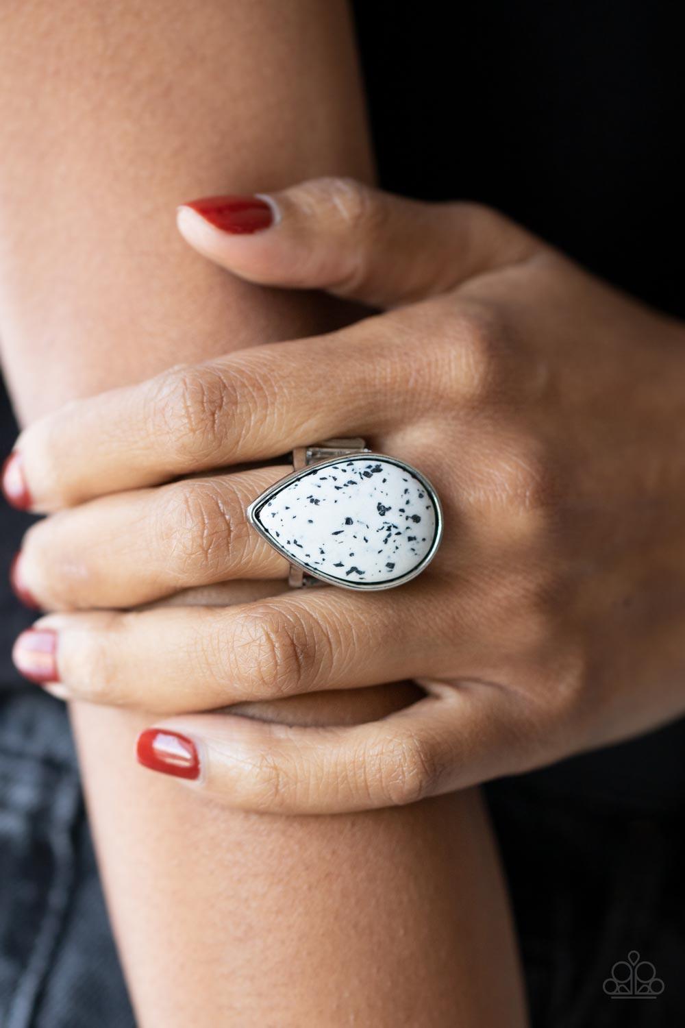 Paparazzi Accessories Stormy Sunrise - White A generous polished white stone infused with black flecks is encased in a simple silver teardrop frame resulting in a seasonal finish atop the finger. Features a stretchy band for a flexible fit. Sold as one in