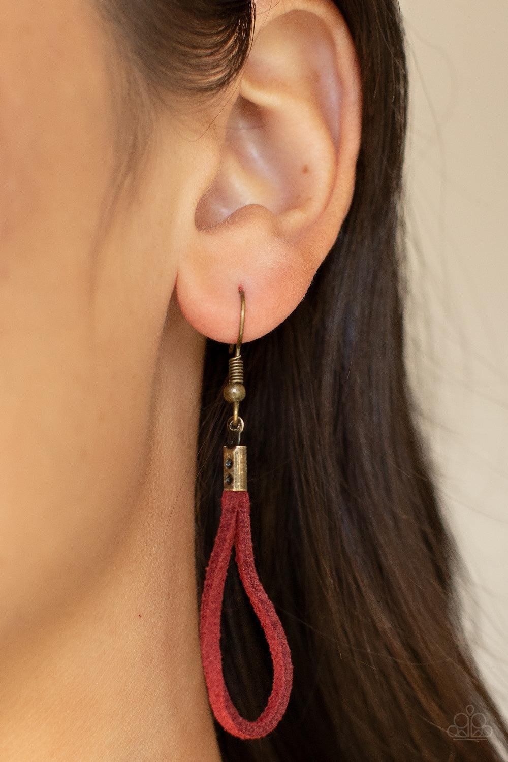 Paparazzi Accessories Noticeably Nomad - Red Flanked by dainty brass rings, a marquise shaped brass bead glides along lengthened strands of rustic red suede, holding in place an oversized brass ring at the bottom for an artisan inspired fashion. Features