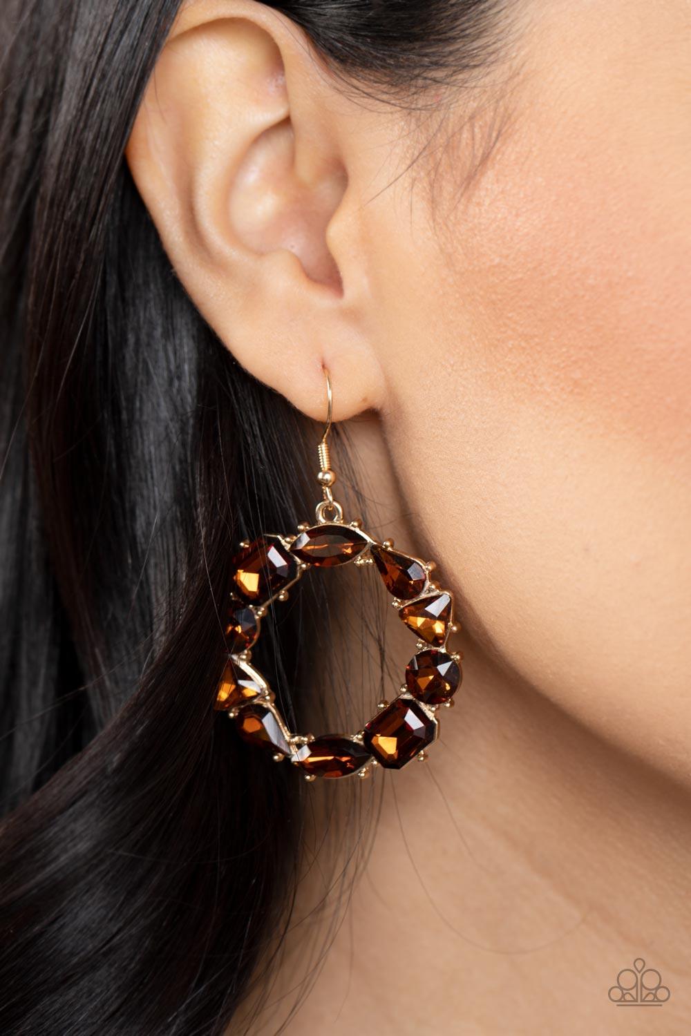 Paparazzi Accessories GLOWING in Circles - Brown Featuring glistening gold fittings, a regal assortment of round, triangular, teardrop, marquise, and emerald cut topaz rhinestones delicately coalesce into a jaw-dropping hoop. Earring attaches to a standar