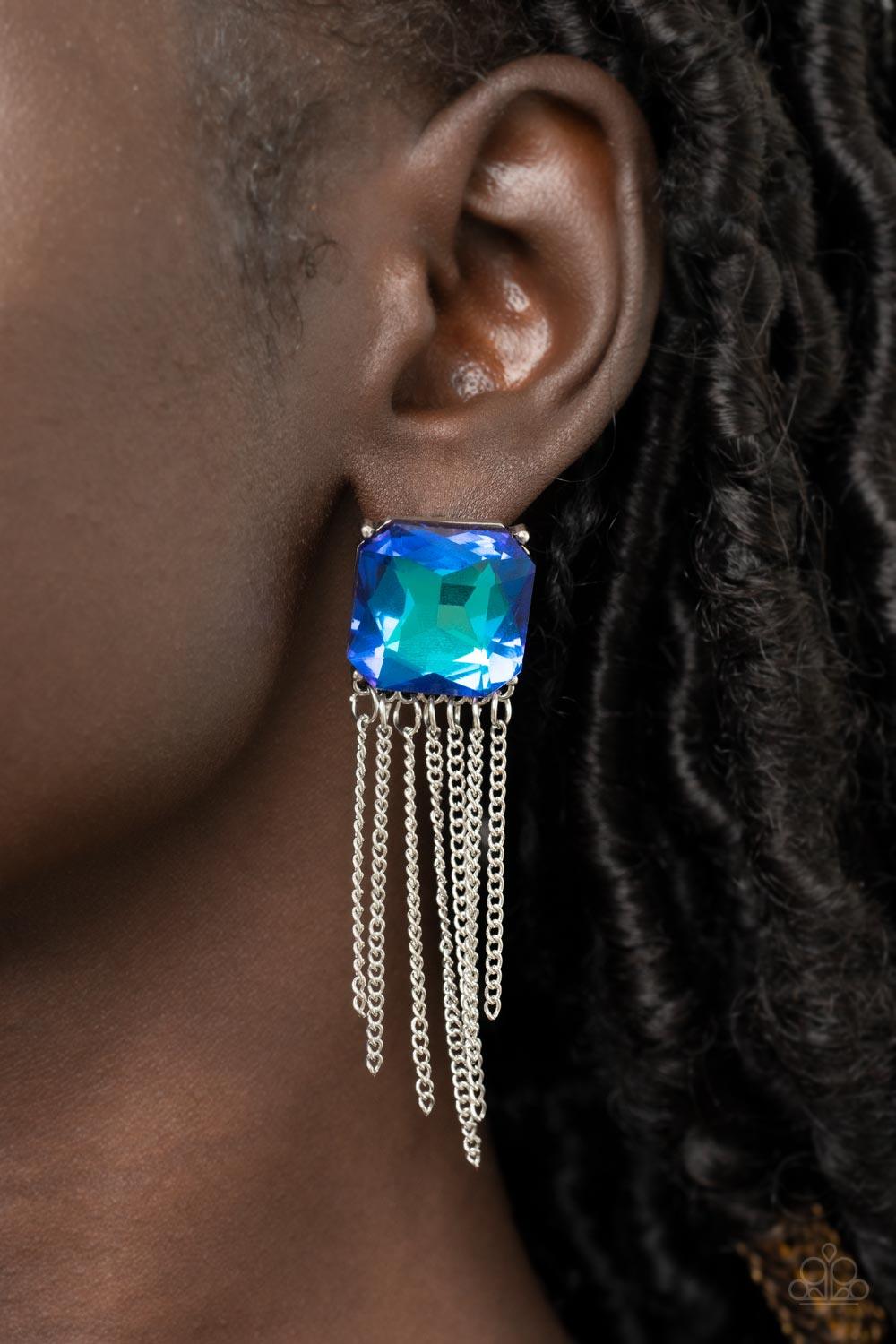 Paparazzi Accessories Supernova Novelty - Blue Featuring a stellar UV shimmer, an oversized radiant cut blue gem is pressed into a pronged silver fitting that gives way to a tapered curtain of silver chains for an out-of-this-world finish. Earring attache