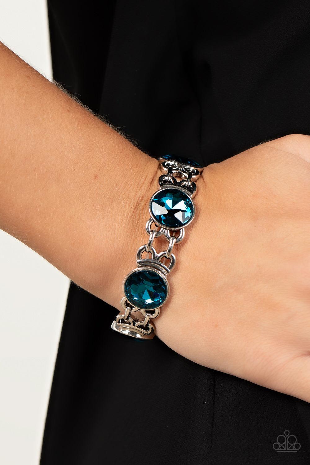 Paparazzi Accessories Devoted to Drama - Blue Featuring edgy chain-like fittings, a sparkly series of oversized blue rhinestones are threaded along stretchy bands around the wrist for a dramatic pop of glitz. Sold as one individual bracelet. Jewelry