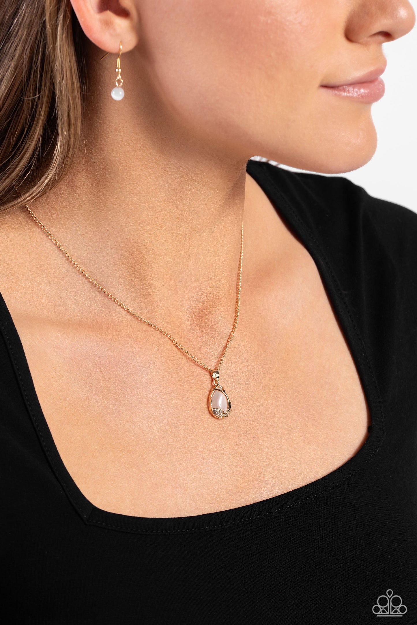 Paparazzi Accessories Top-Notch Trinket - Gold Dotted in dainty gold studs and glittery white rhinestones, leafy gold frames delicately fold around the bottom of a white cat's eye stone teardrop, resulting in an ethereal pendant below the collar. Features