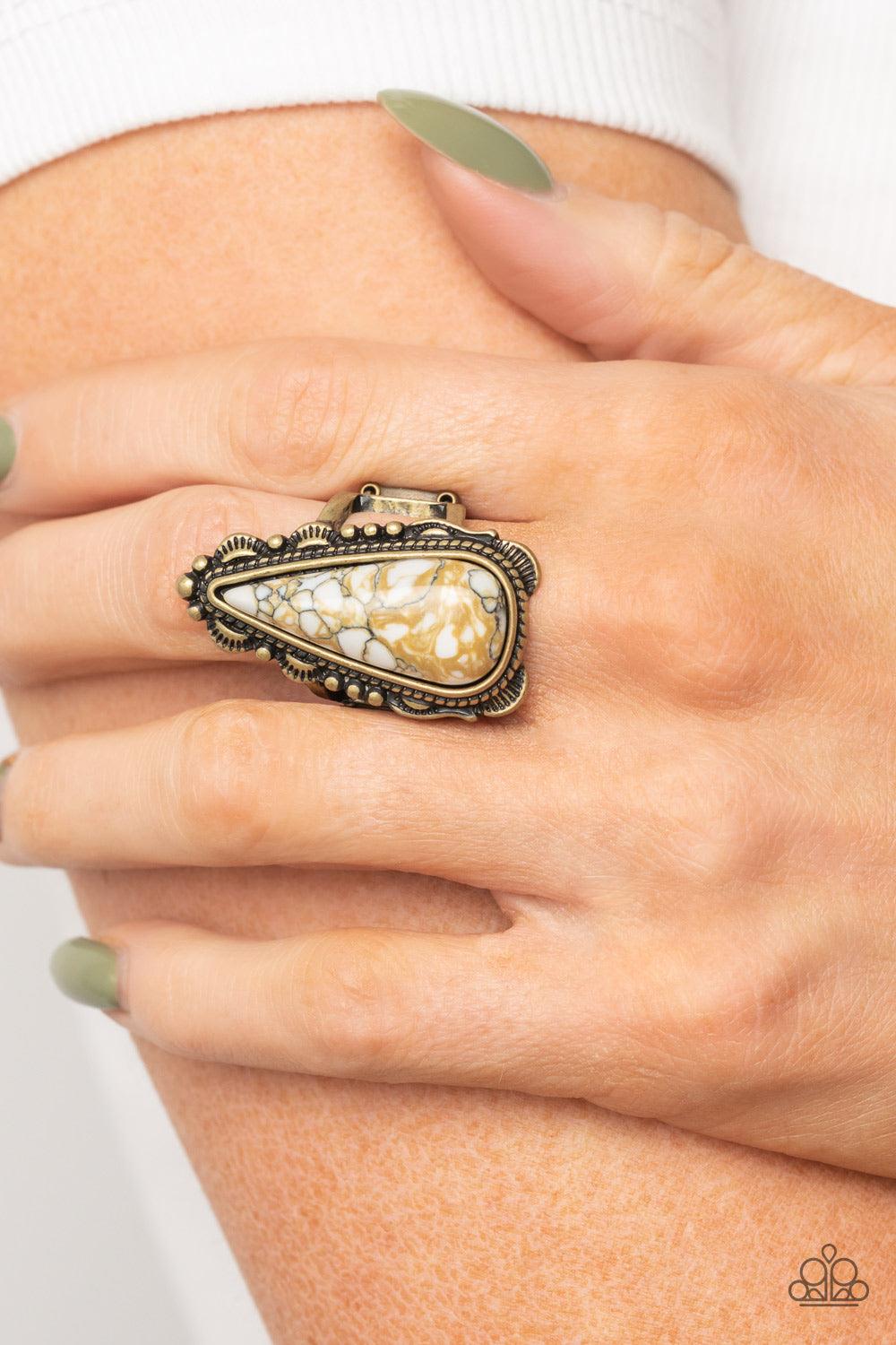 Paparazzi Accessories Canyon Collector - Brass Infused with brassy shimmer, an oversized white teardrop stone is nestled inside a brass frame studded and embellished in antiqued brass details for an authentic finish. Features a stretchy band for a flexibl