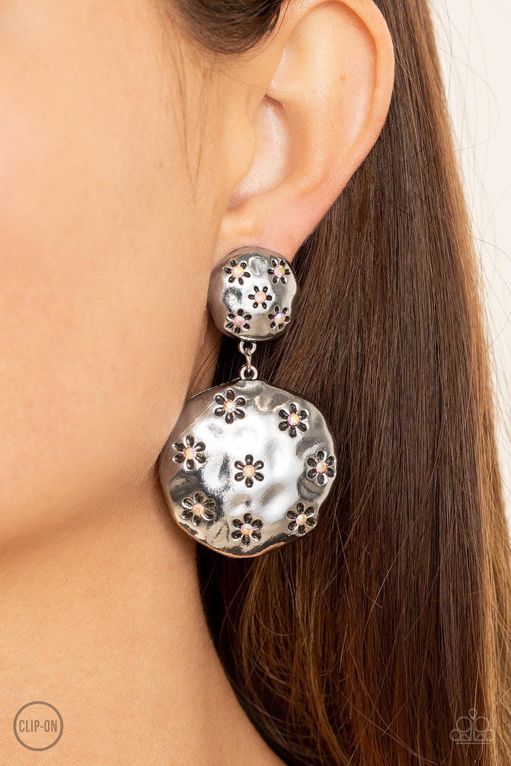 Paparazzi Accessories Industrial Fairytale - Pink *Clip-On Dotted with dainty iridescent pink rhinestone centers, an antiqued floral pattern is stamped across the fronts of two hammered silver discs that delicately connect into a rustic lure. Earring atta