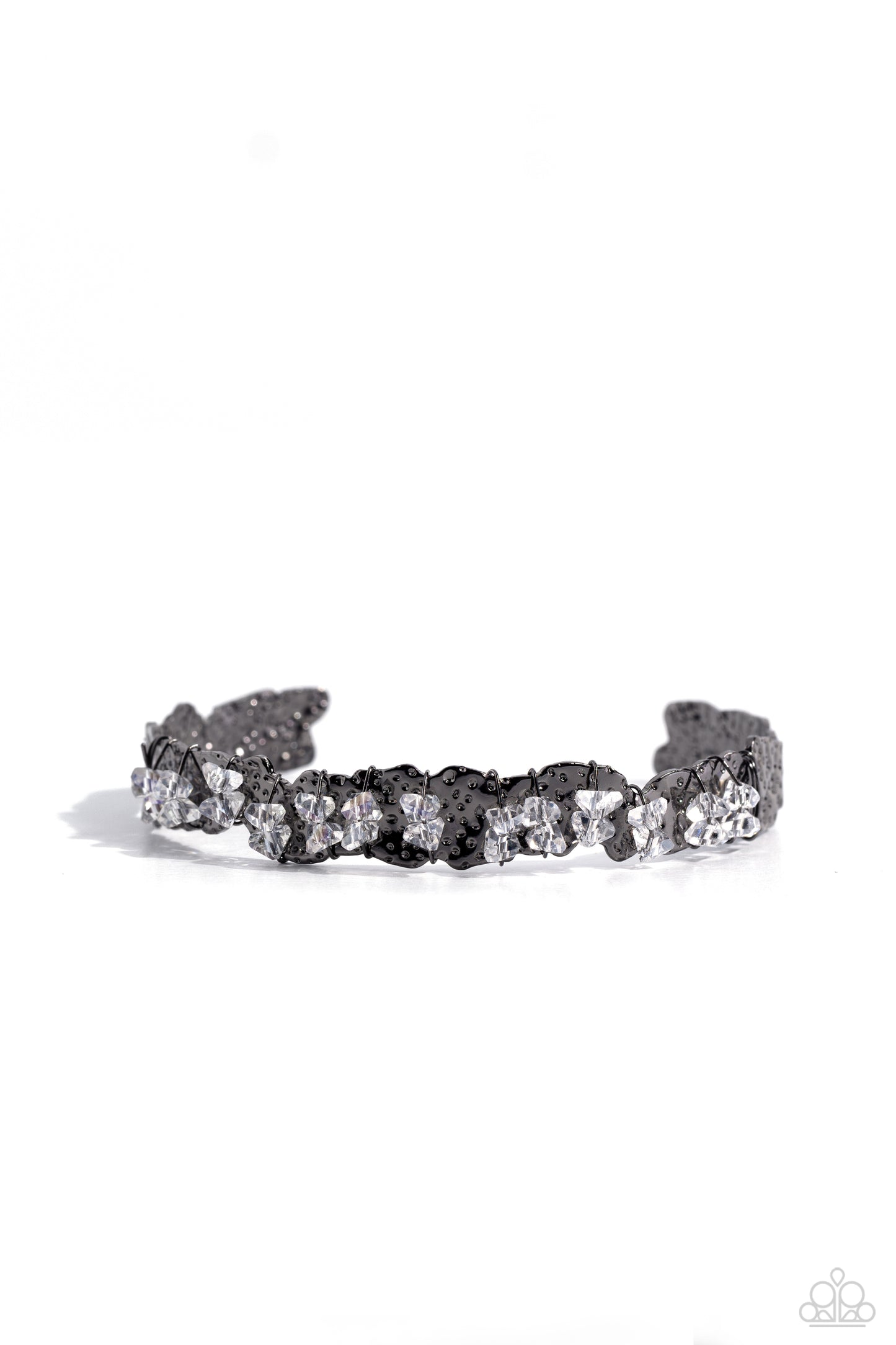 Paparazzi Accessories Enticingly Icy - Black Featuring raw cuts, pairs of icy white gems are fitted in place across the center of a hammered and asymmetrical gunmetal cuff with dainty gunmetal wires. Reminiscent of ice, the sharp rhinestone accents are ha