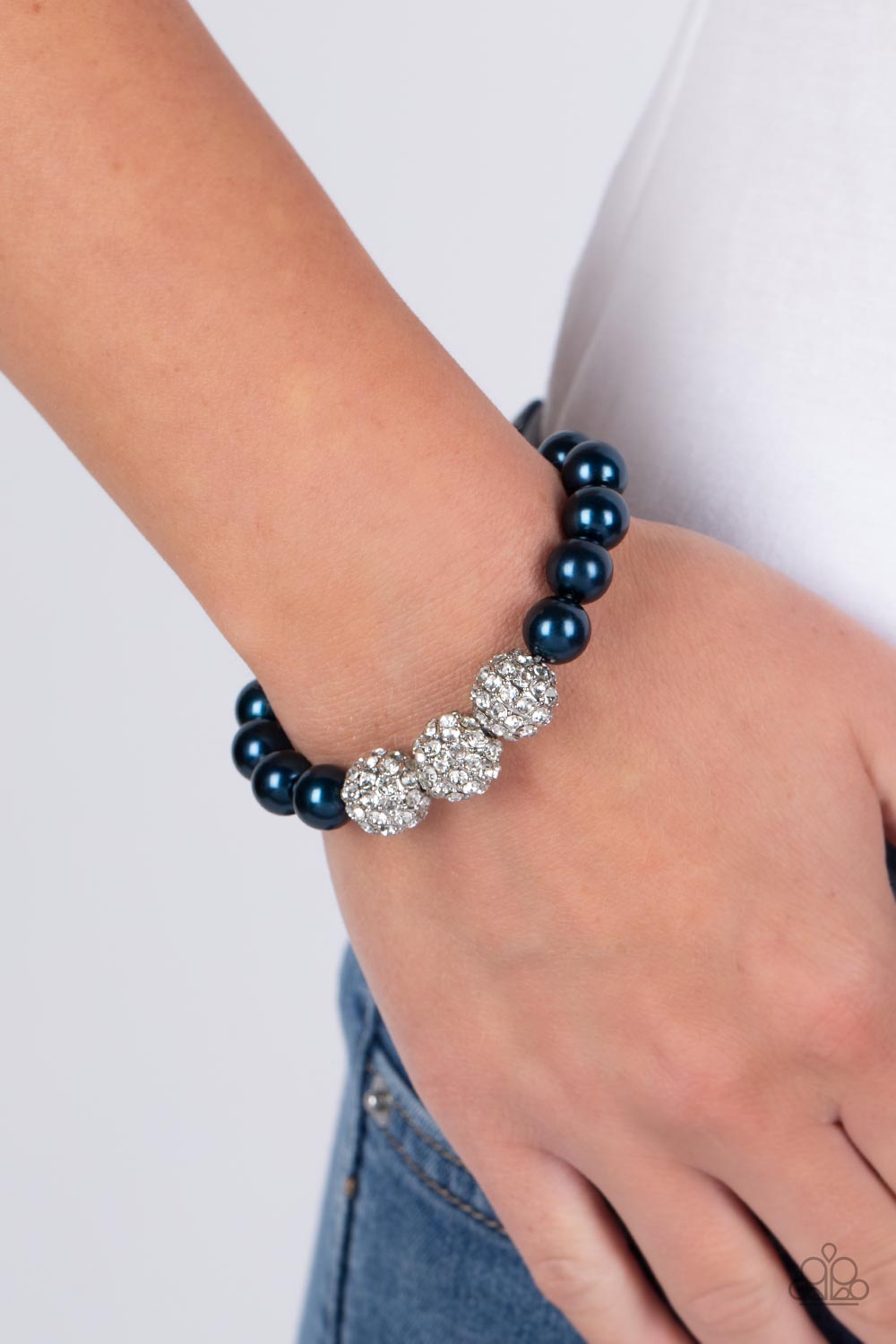 Paparazzi Accessories Breathtaking Ball - Blue A trio of silver beads encrusted in rhinestones is centered along a strand of classic Montanna pearls. The beads are threaded along a stretchy band, wrapping around the wrist in a refined finish. Sold as one