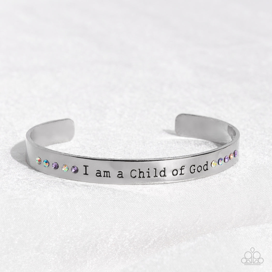 Paparazzi Accessories Divine Display - Multi A shiny silver cuff stamped with the phrase "I am a Child of God" encircles the wrist. Dainty sapphire, violet and iridescent rhinestones shimmer at the borders of the phrase for a whimsical finish. Due to its