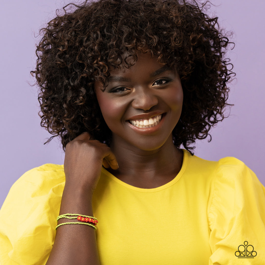 Paparazzi Accessories Buzzworthy Botanicals - Red Strung along the entirety of three elastic stretchy bands, apple green seed beads coalesce around the wrist. Featured on one of the bands of green seed beads, blooming red seed bead flowers, with yellow se