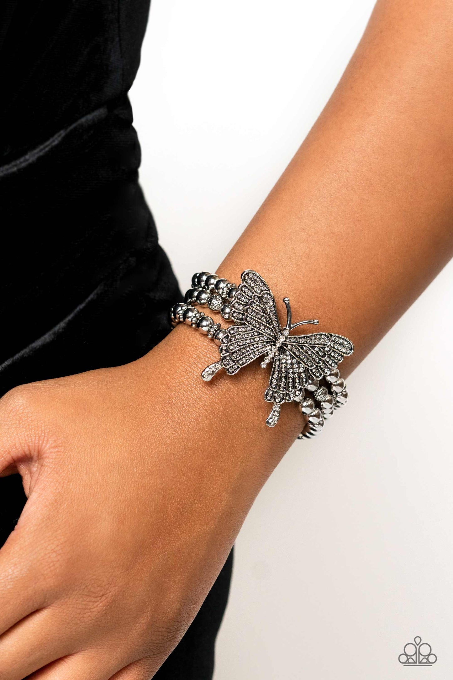 Paparazzi Accessories First WINGS First - White Strung along elastic stretchy bands, a trio of silver and textured silver beads and accents wrap around the wrist. Featured atop the beaded collection, an oversized silver butterfly, with intricate details,