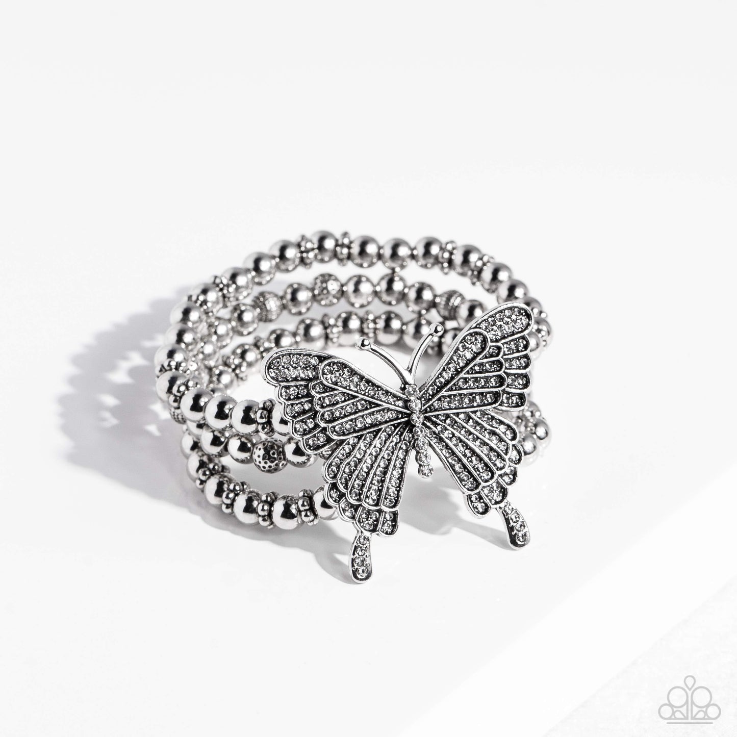Paparazzi Accessories First WINGS First - White Strung along elastic stretchy bands, a trio of silver and textured silver beads and accents wrap around the wrist. Featured atop the beaded collection, an oversized silver butterfly, with intricate details,