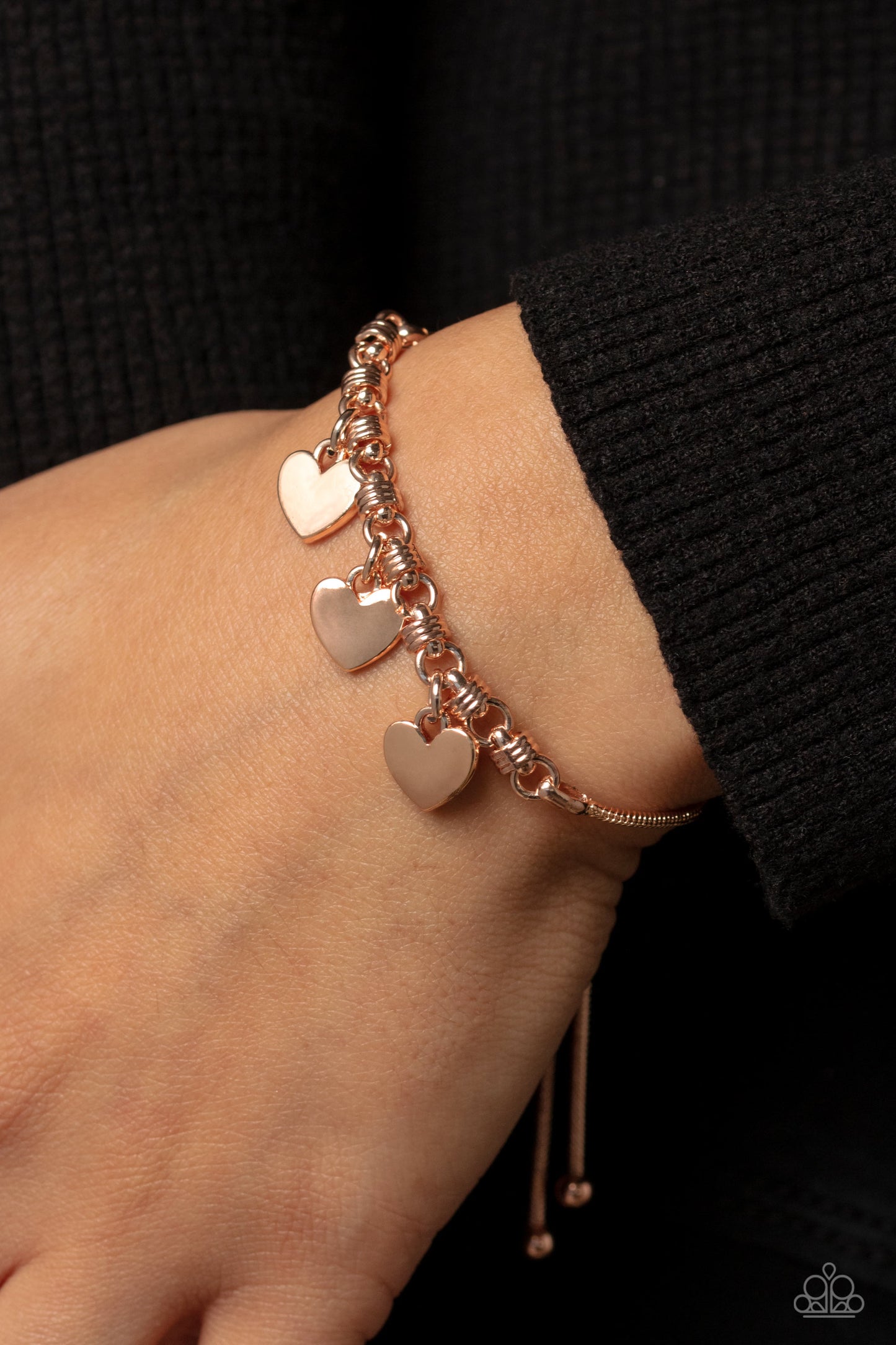 Paparazzi Accessories Romance Tale - Rose Gold Dangling from a rose gold snake chain, a trio of rose gold hearts link across the wrist for a dash of swoon-worthy sheen. Infused along the heart chain, rose gold spiral-like accents add additional texture to