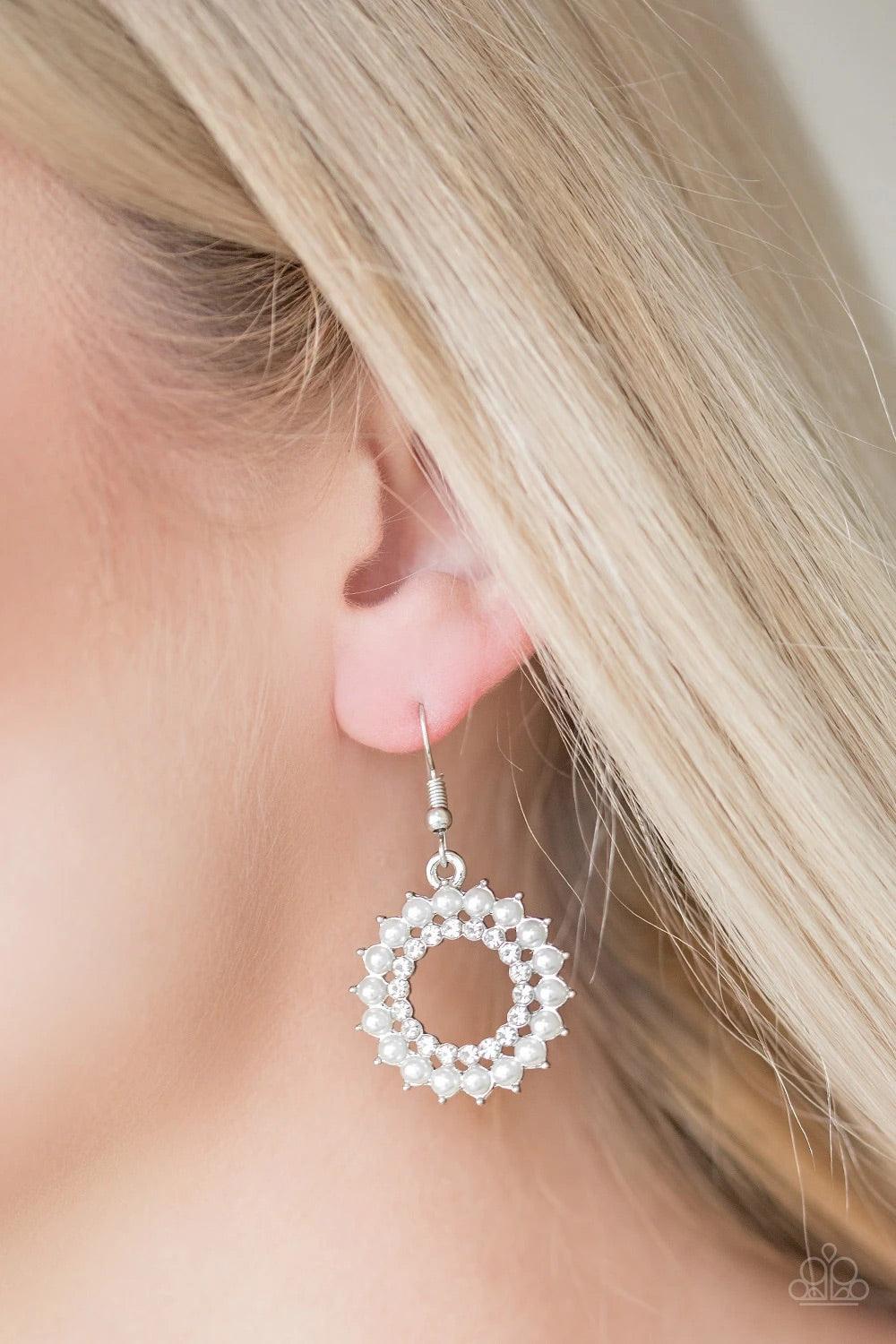 Paparazzi Accessories Wreathed in Radiance - White Dainty white pearls spin around a radiant white rhinestone center, coalescing into a refined hoop. Earring attaches to a standard fishhook fitting. Sold as one pair of earrings. Jewelry