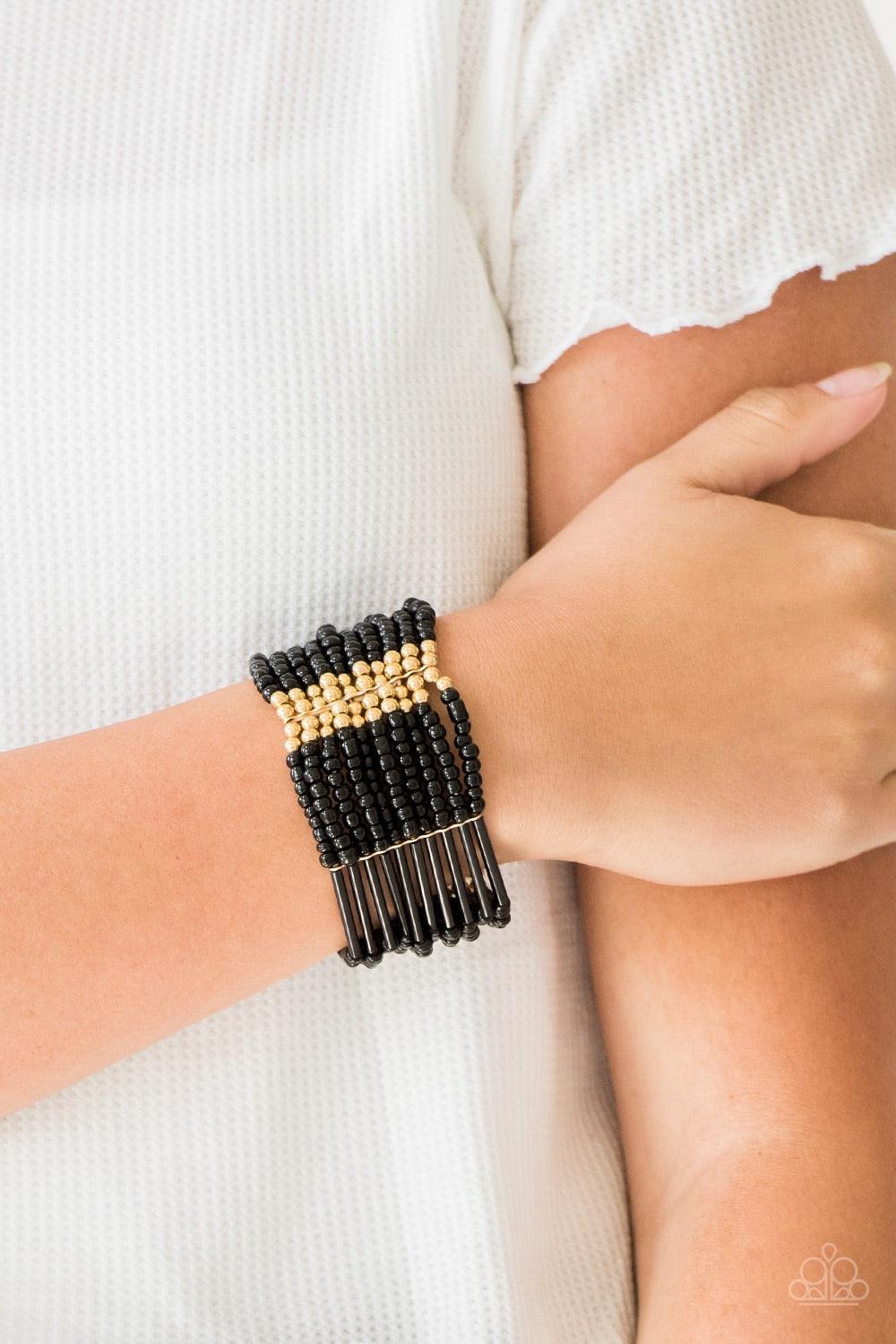 Paparazzi Accessories Rural Retreat - Gold Joined together with metallic fittings, black seed beads are threaded along stretchy elastic bands. Sections of gold beads are sprinkled along the edgy layers, adding hints of shimmer to the seasonal palette. Jew