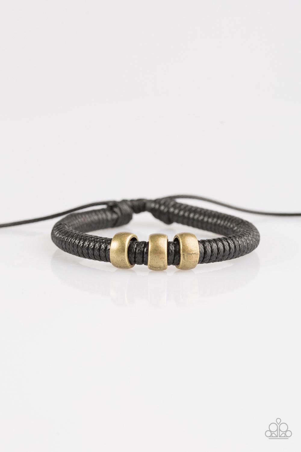 Paparazzi Accessories One For The Trail - Black Shiny black twine wraps around a black cord, creating an urban look around the wrist. Shiny brass beads slide along the cording for a rugged finish. Features an adjustable sliding knot closure. Jewelry