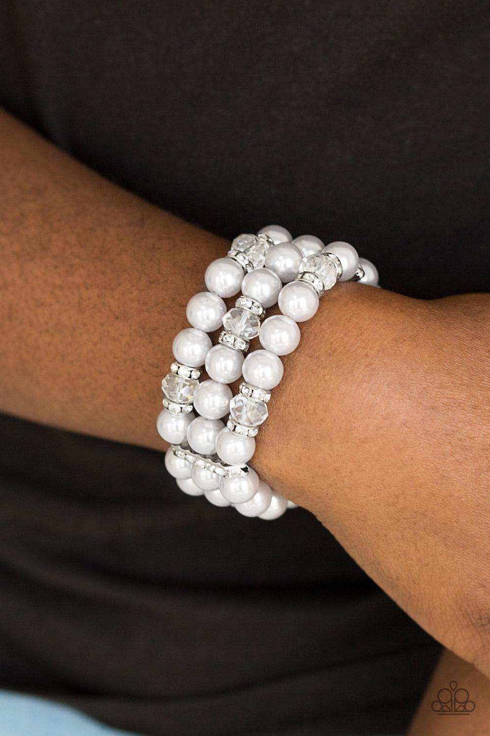 Paparazzi Accessories Undeniable Dapper ~Silver Pinched between white rhinestone encrusted frames, white rhinestone encrusted rings, crystal-beads, and silver pearls are threaded along elastic stretchy bands for a glamorous look.