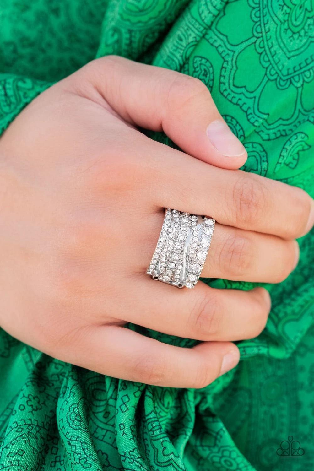 Paparazzi Accessories Exclusive Elegance - White Row after row of radiantly mismatched white rhinestones and glistening silver bands haphazardly stack across the finger, coalescing into a dramatic display of dazzle. Features a stretchy band for a flexible