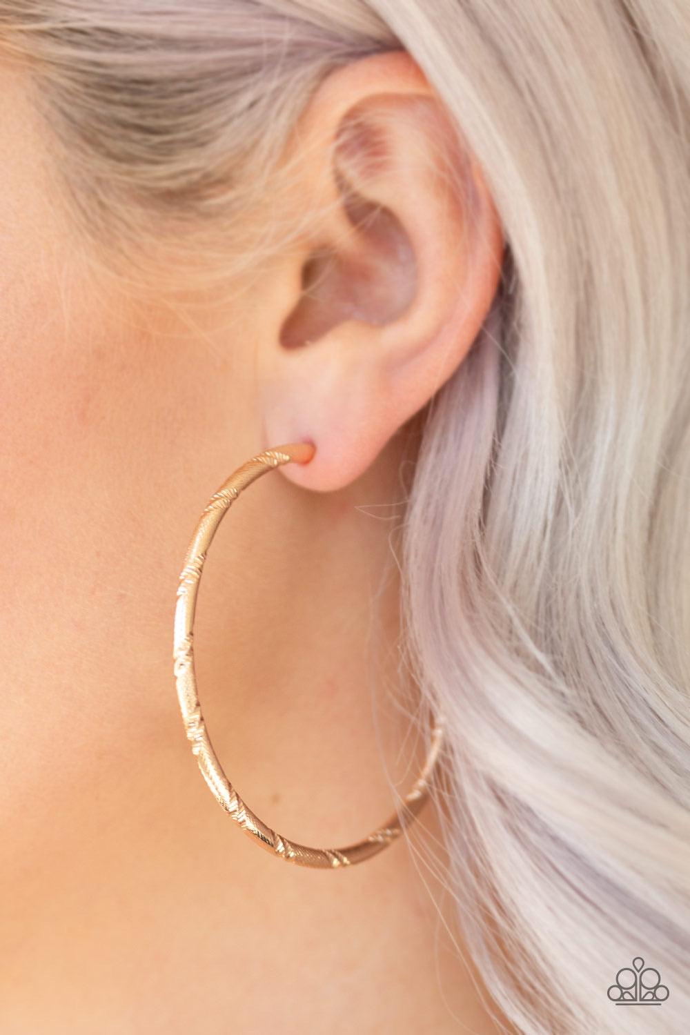 Paparazzi Accessories A Double Take - Gold Etched in ribbons of diamond-cut shimmer, a shiny gold hoop curls around the ear for a classic look. Earring attaches to a standard post fitting. Hoop measures 2 1/4" in diameter. Sold as one pair of hoop earring